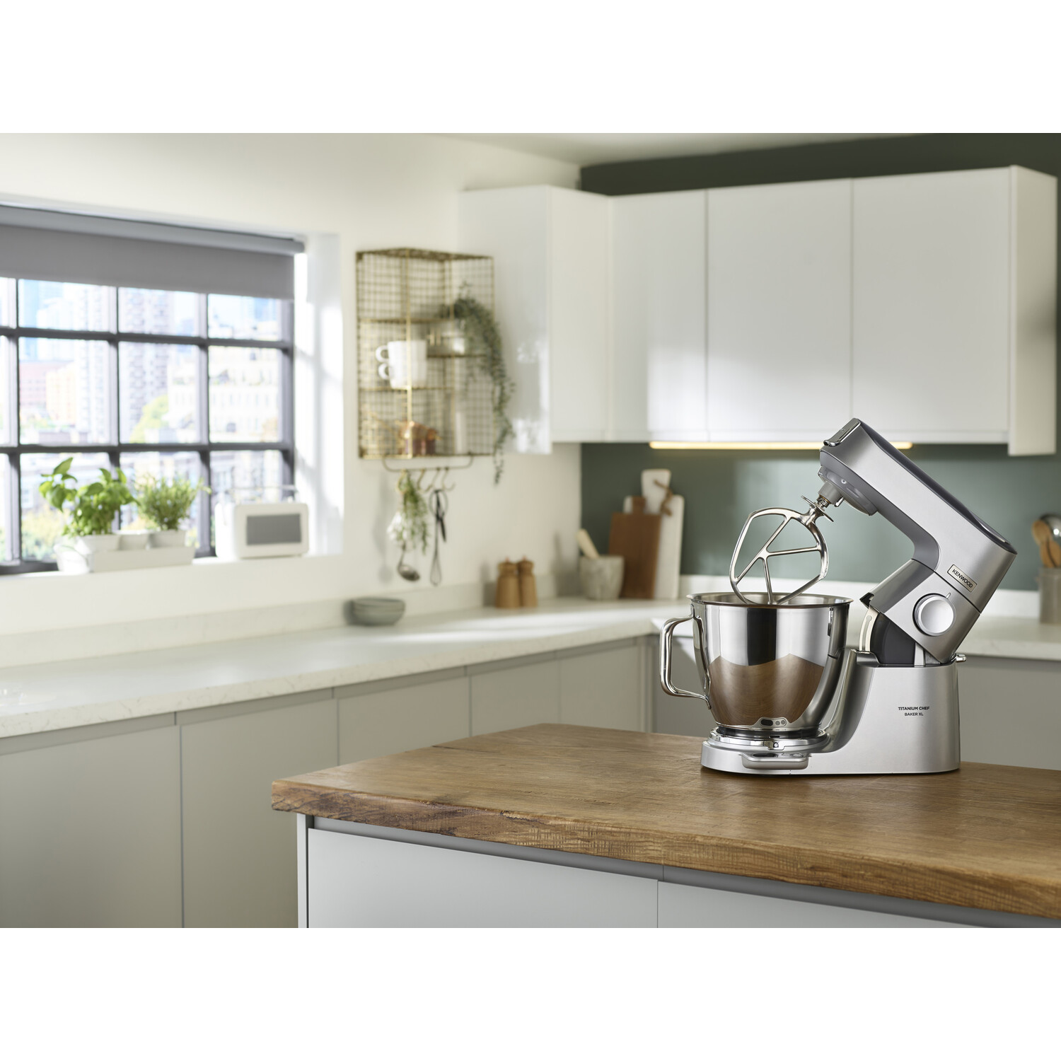 Een zilveren keukenmixer met een kom op een houten aanrecht in een keuken.