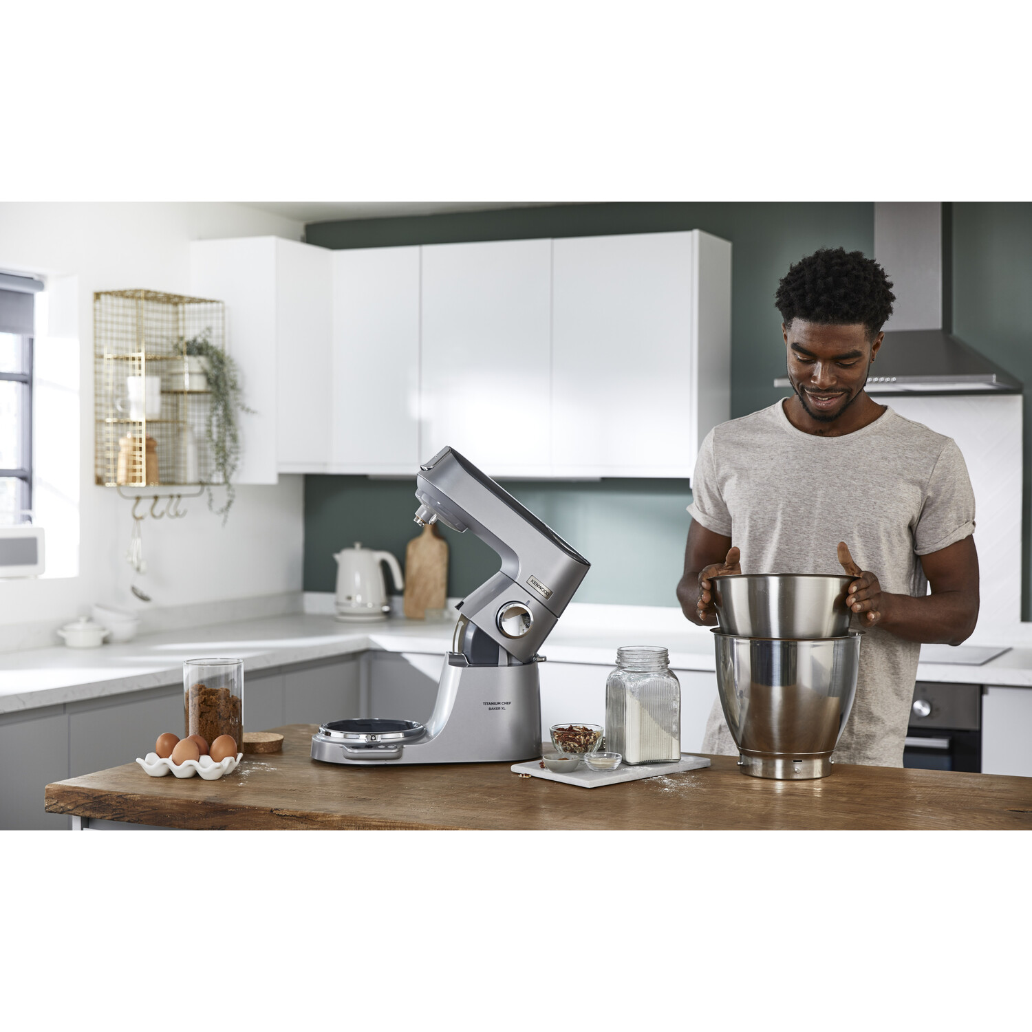 Een man in een keuken met een keukenmachine en kommen, die zich klaarmaakt om te koken.