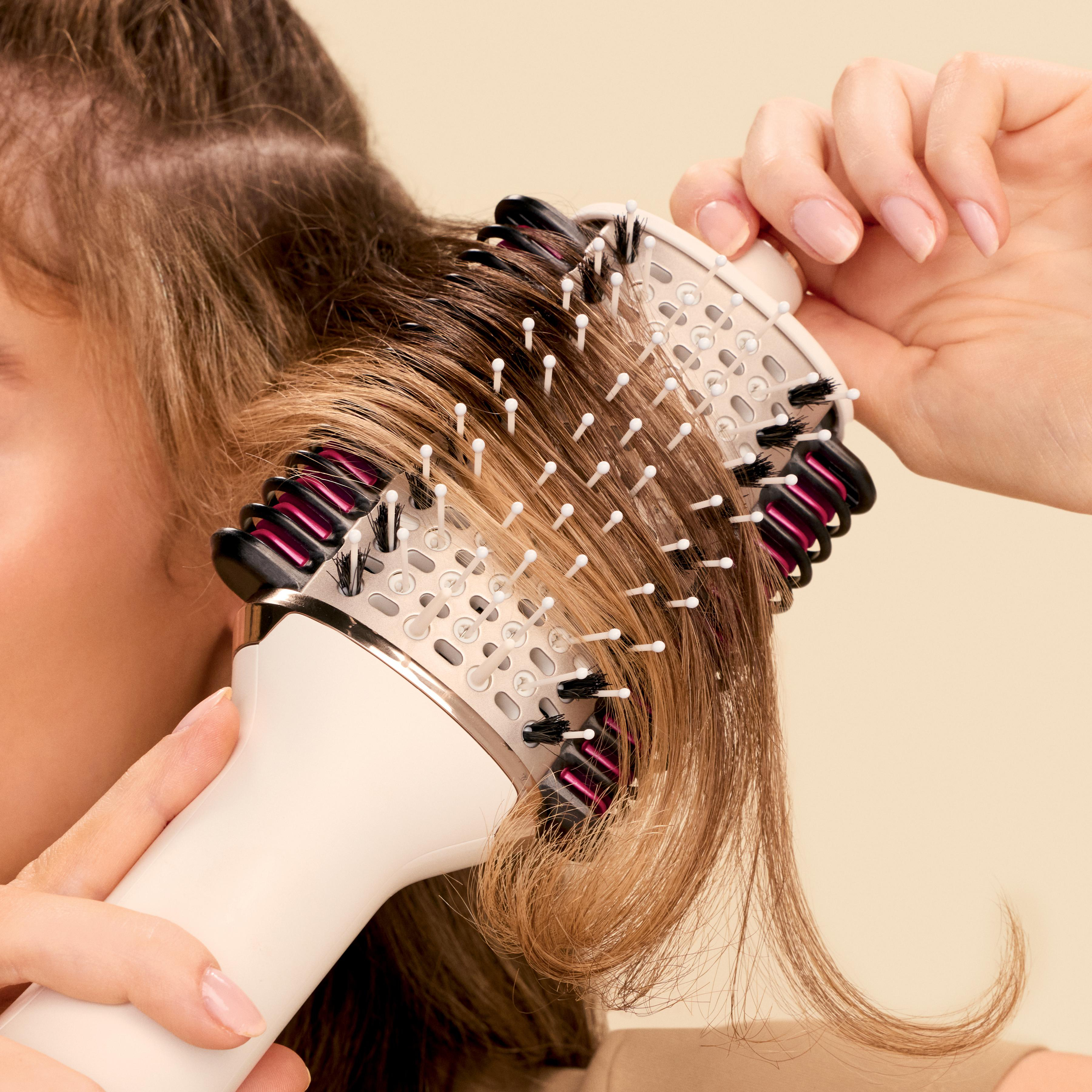 Eine Person, die eine Haarbürste auf braunem Haar verwendet, Nahaufnahme.