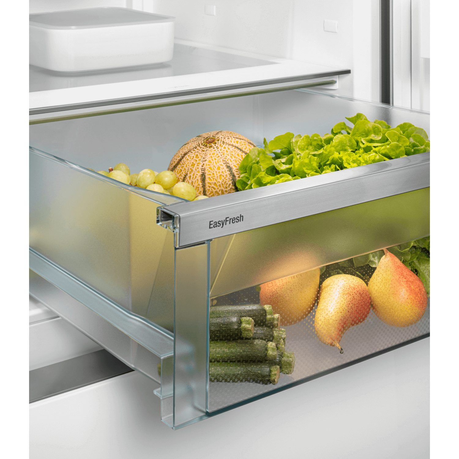 Refrigerator drawer full of fruits and vegetables, lit up.