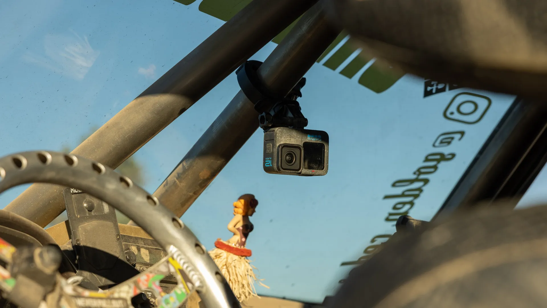 Une caméra GoPro montée à l'intérieur d'une voiture, face vers l'avant. Une petite figurine est visible sur le tableau de bord.