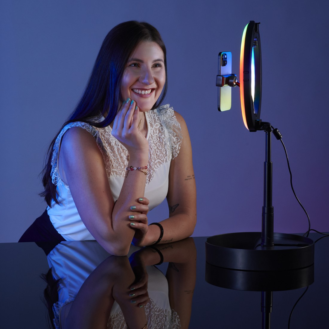 Frau lächelt, benutzt ein Telefon mit einem Ringlicht.