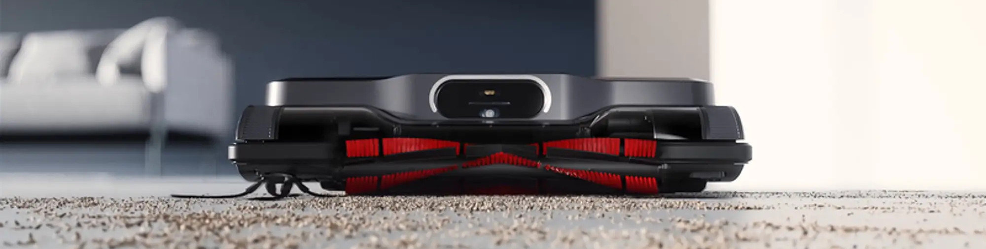 Odkurzacz robot na brudnej podłodze. Czarne i szare urządzenie z czerwonymi szczotkami.