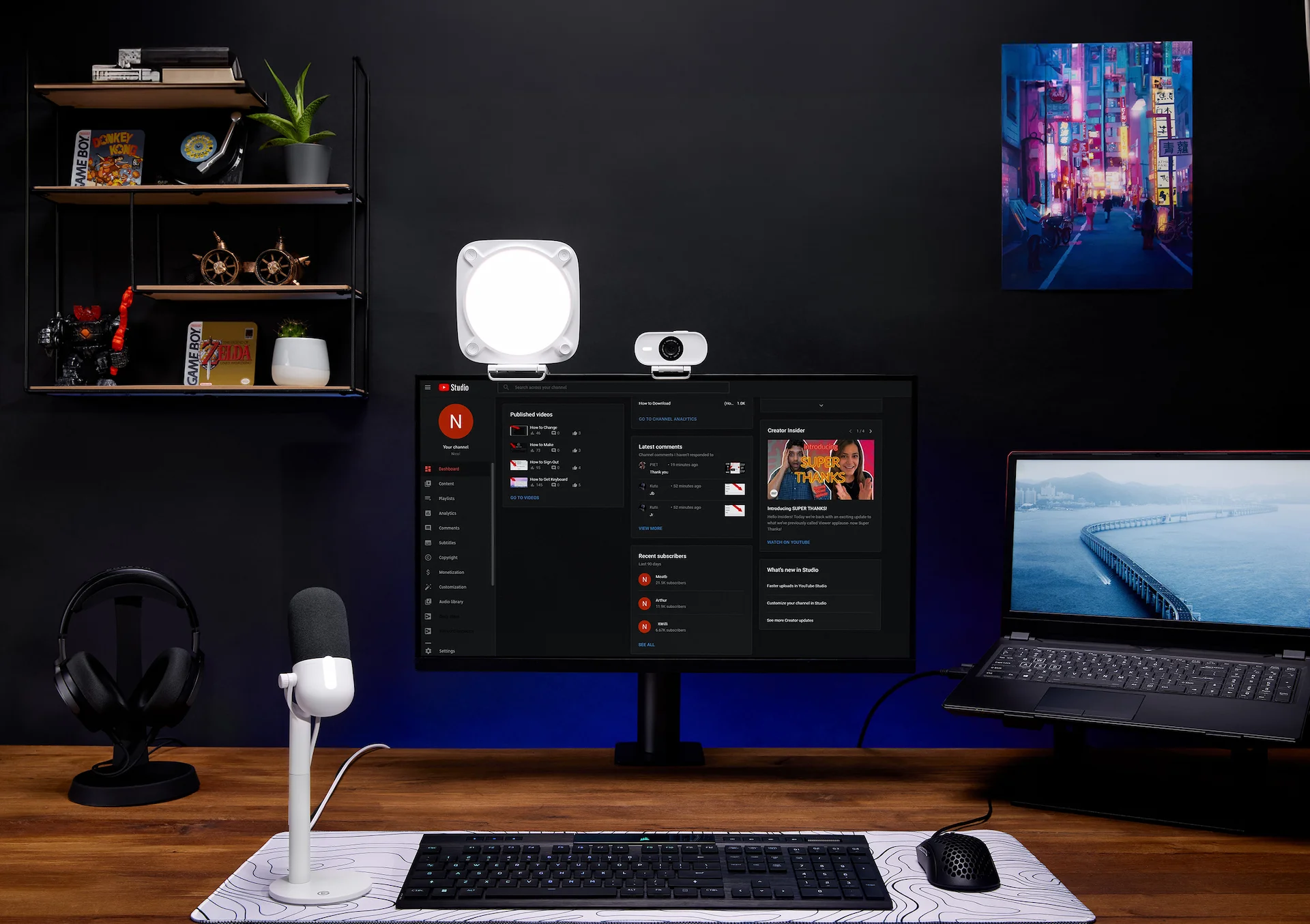 Ein Schreibtisch mit Monitor, Webcam, Mikrofon, Tastatur und Zubehör.