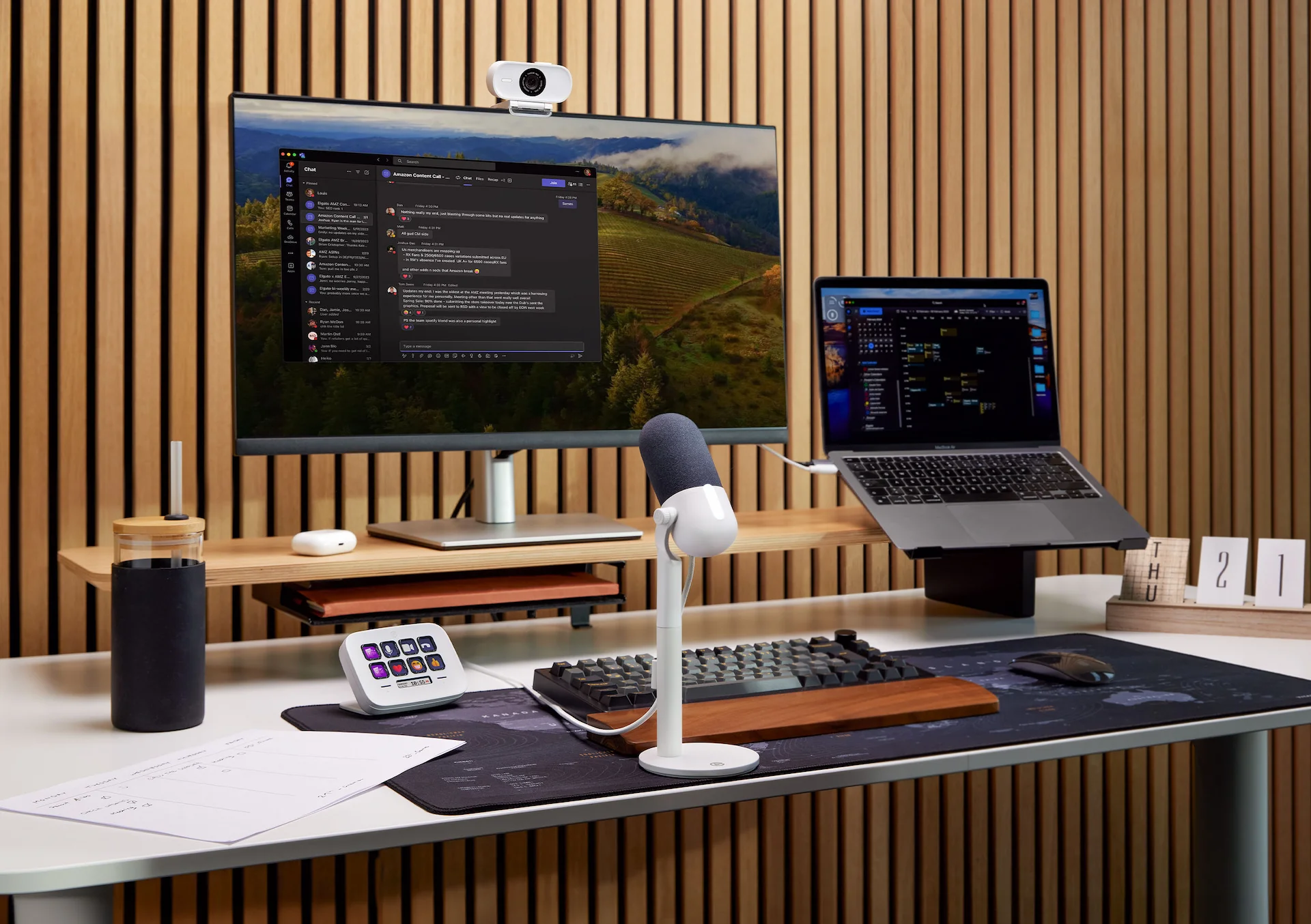 Arbeitsplatz mit Monitor, Laptop, Schreibtisch-Setup mit Mikrofon, Tastatur und Zubehör.