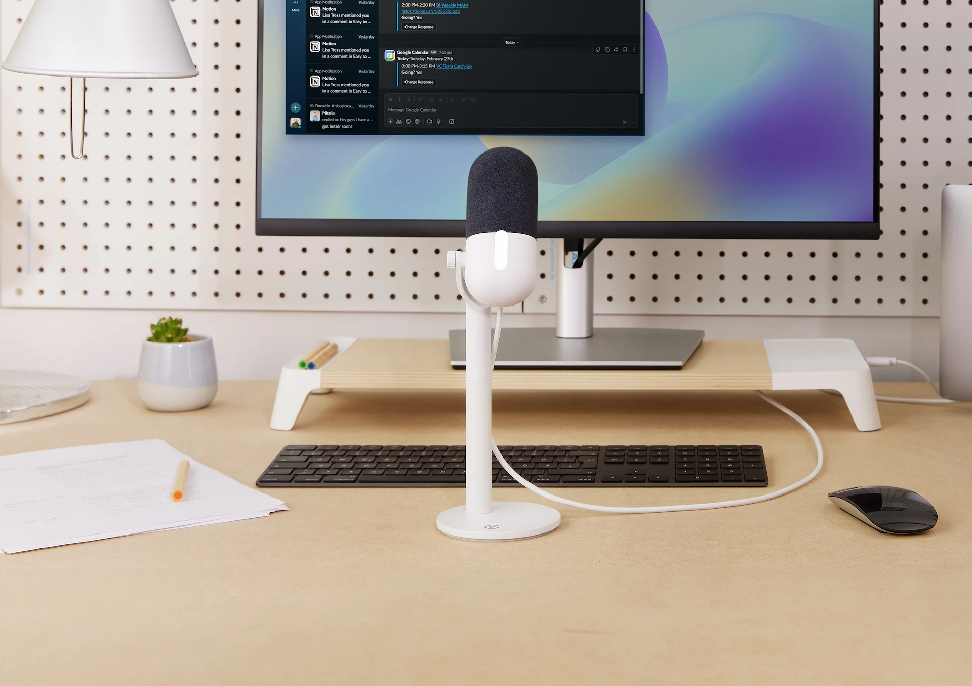 Schreibtisch mit Mikrofon, Monitor mit Webseite und Zubehör.
