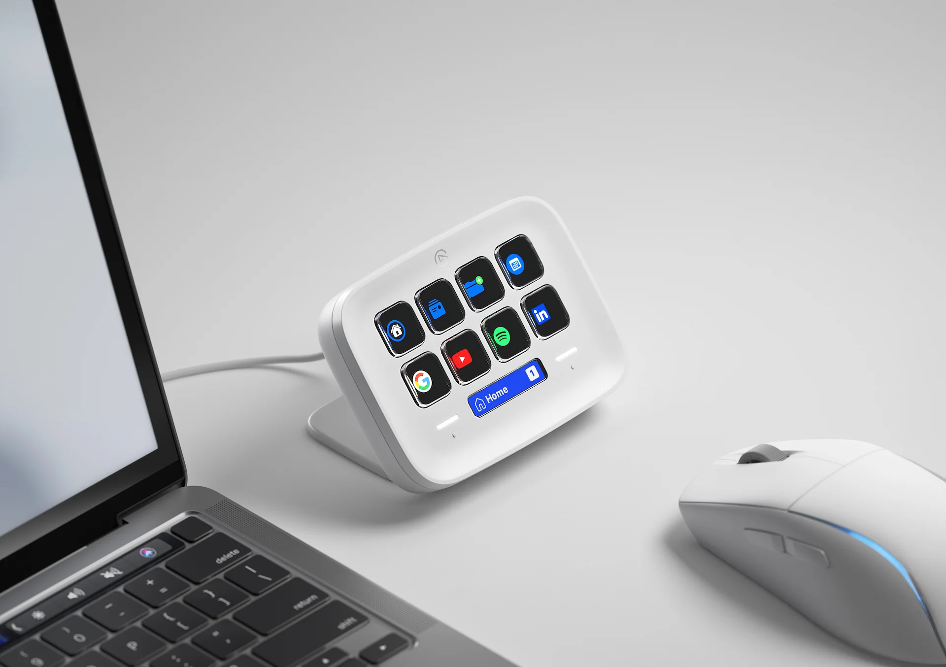 Weißes Elgato Stream Deck mit verschiedenen App-Symbolen, neben einem Laptop und einer weißen Maus.