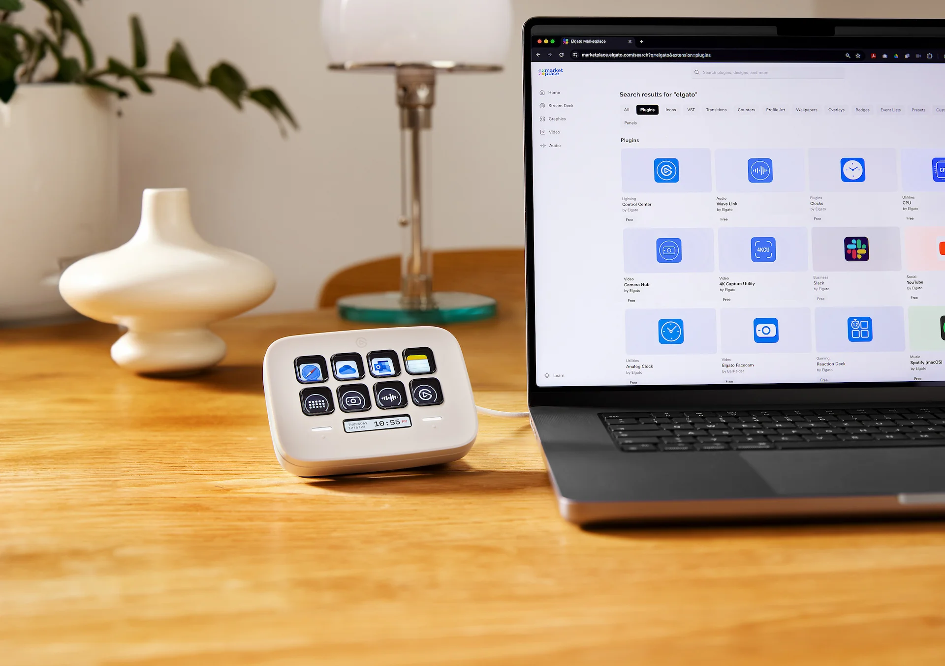 Ein Schreibtisch mit einem Laptop, einem Stream Deck, einer weißen Vase und einer Schreibtischlampe. Der Laptop zeigt einen Plugin-Store.