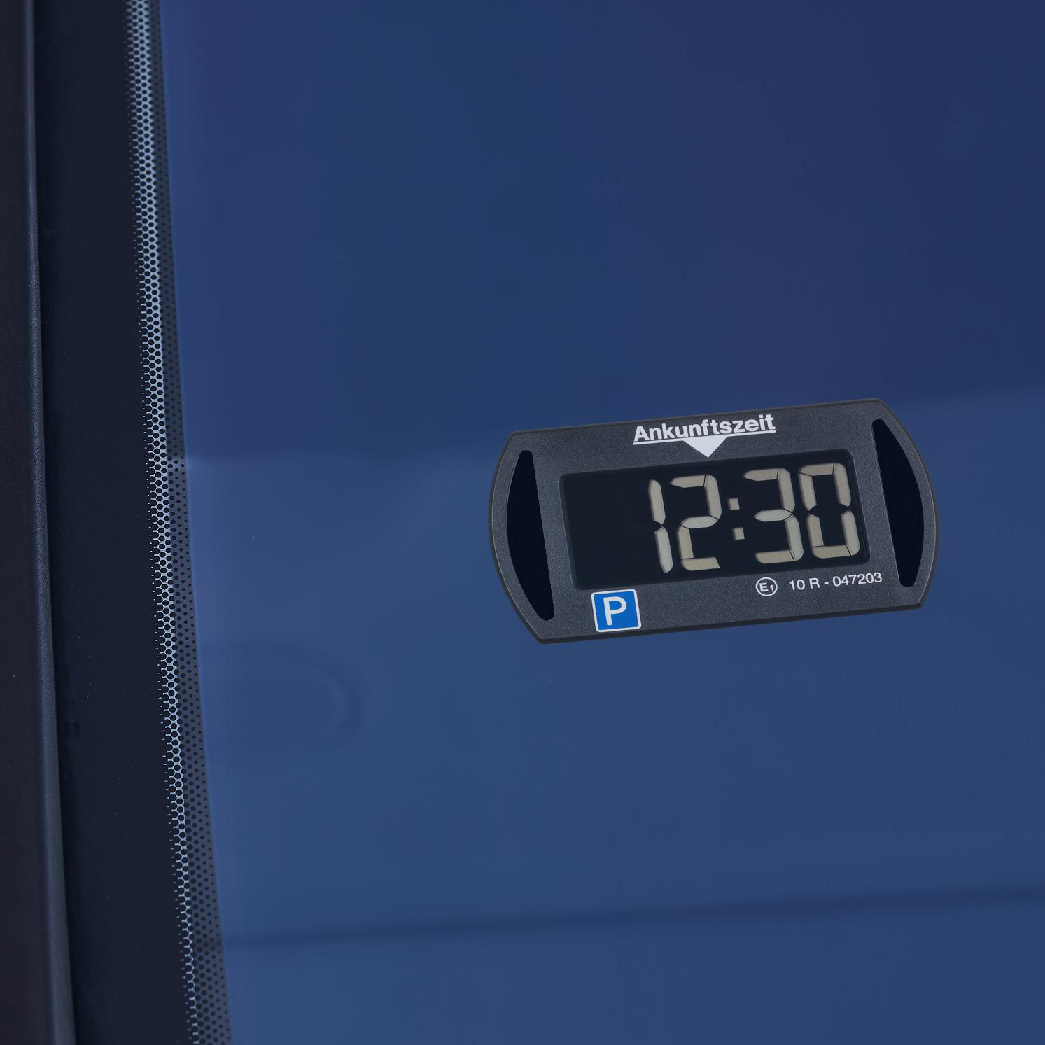 Schwarze Parkscheibe mit 12:30 auf einer Autoscheibe.