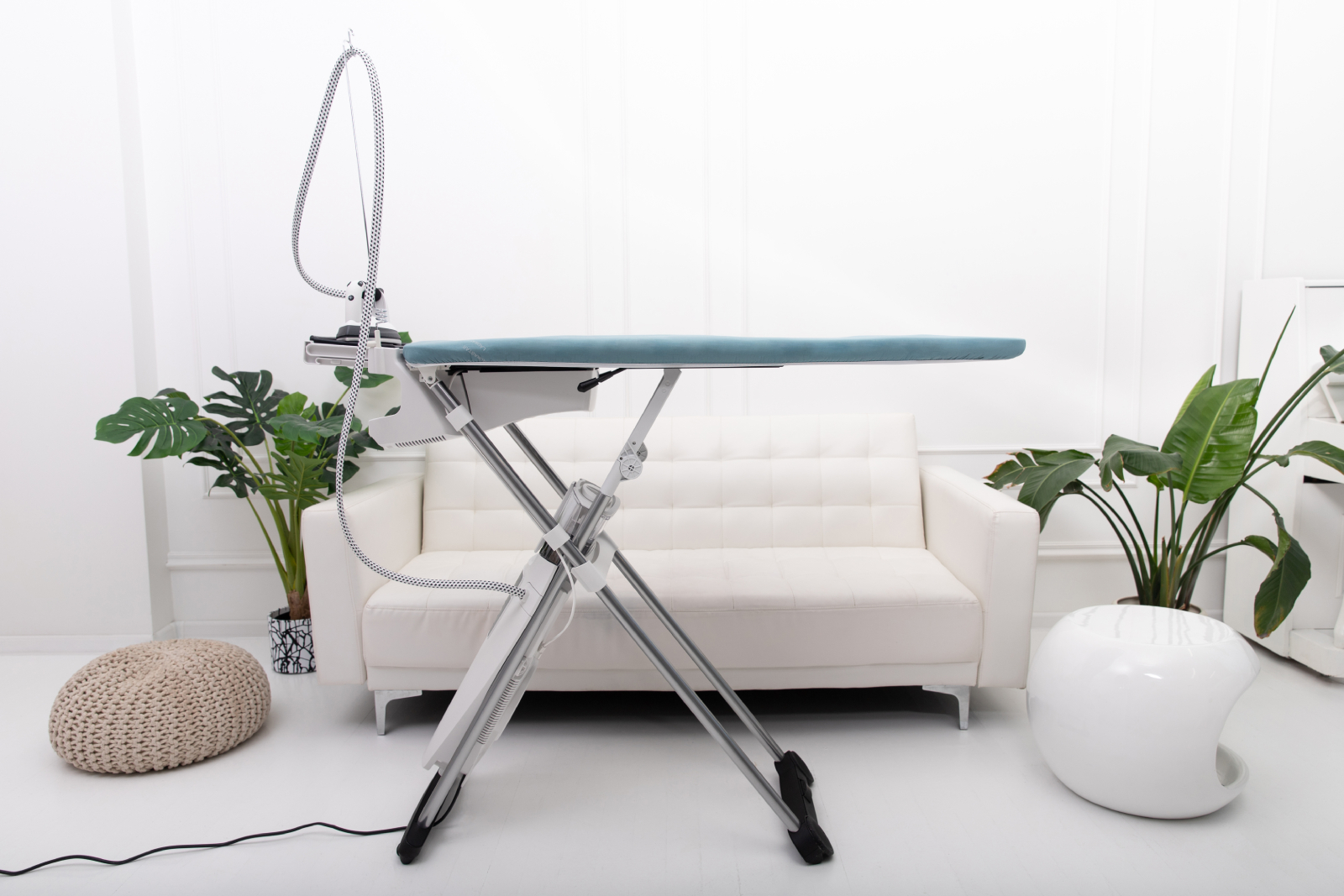 Deska do prasowania z żelazkiem parowym i sofą.