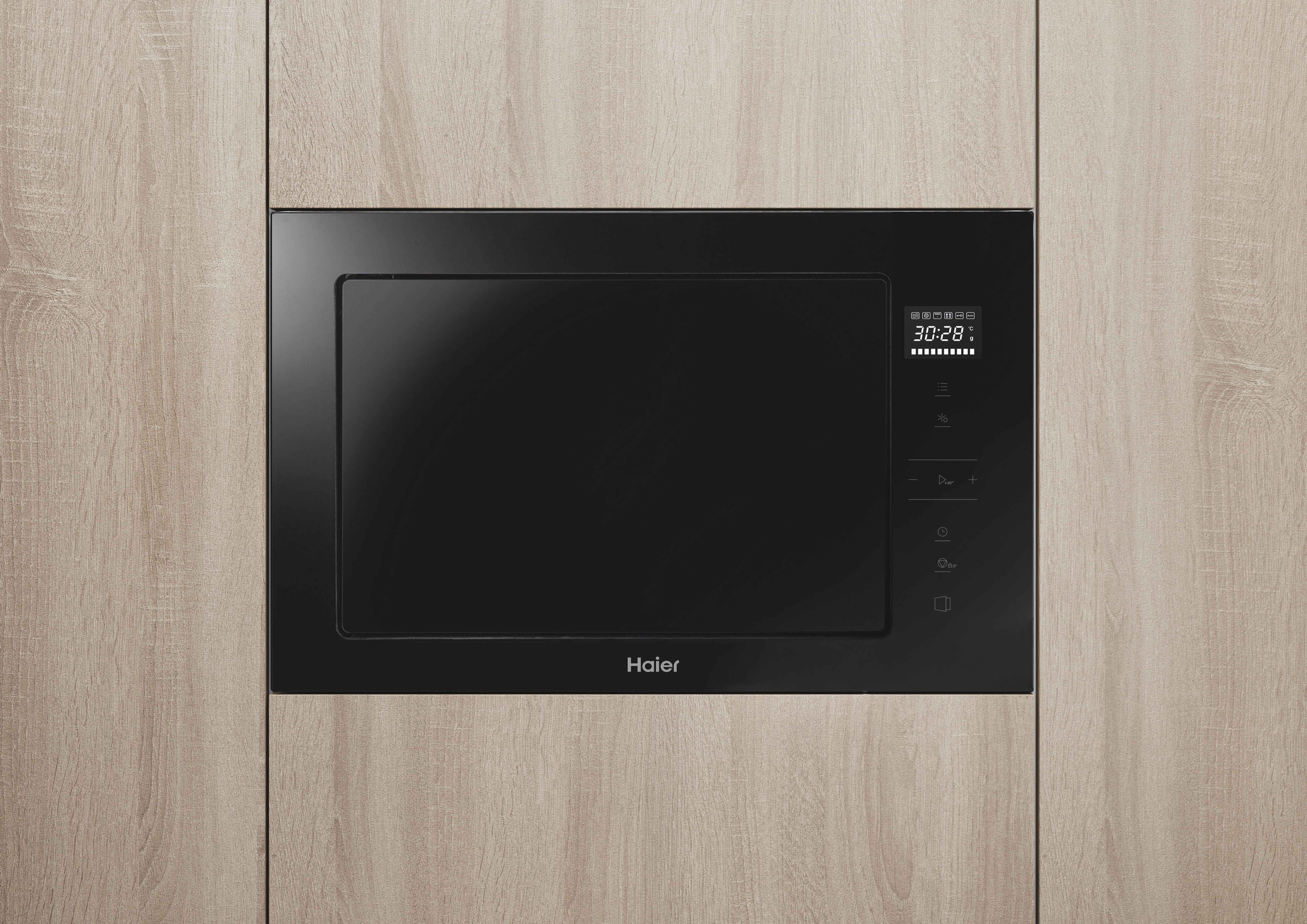 Horno microondas negro empotrado. En un mueble de madera. Logotipo de la marca Haier.