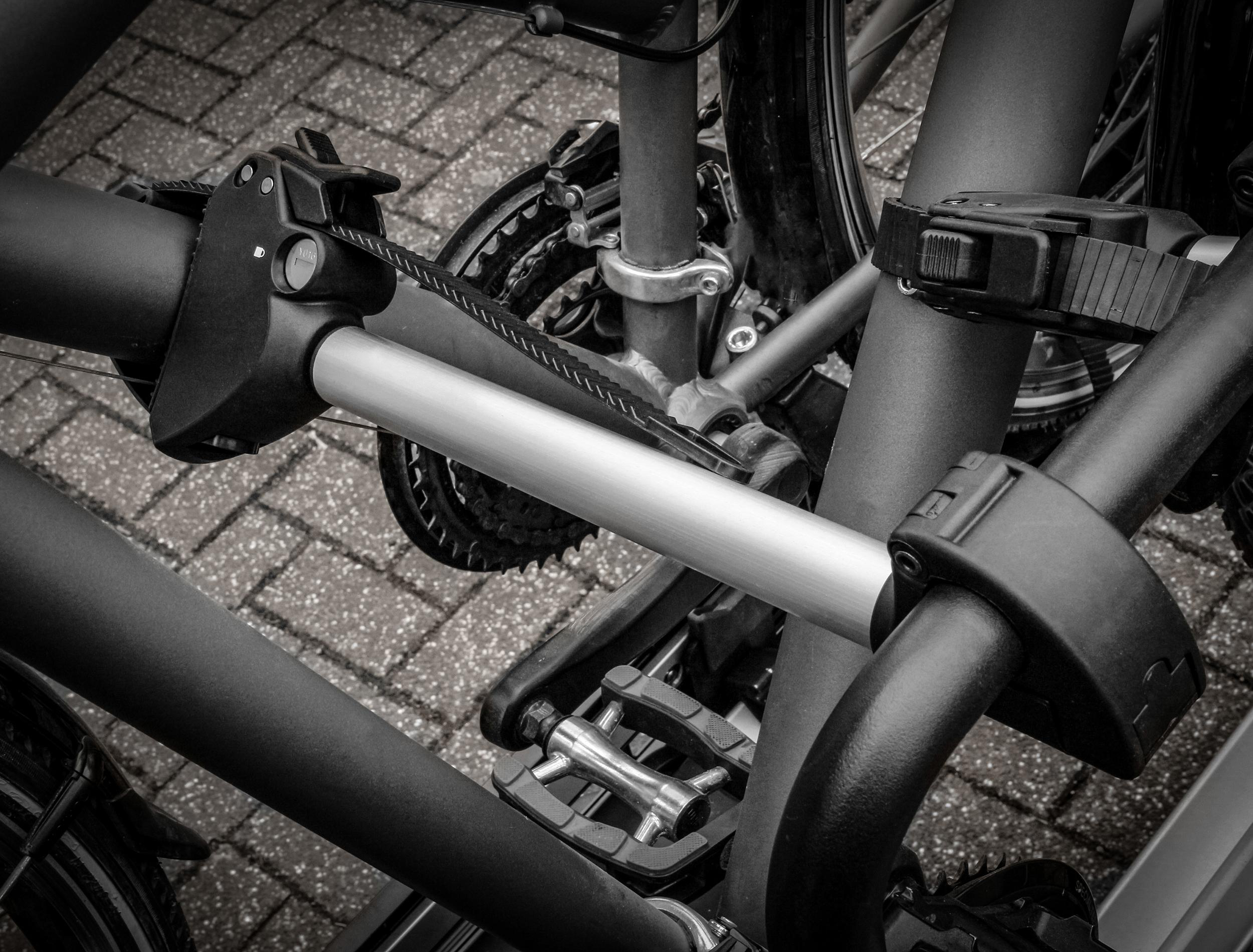 Nahaufnahme eines schwarz-silbernen Fahrradträgers, mit sichtbaren Fahrradteilen.
