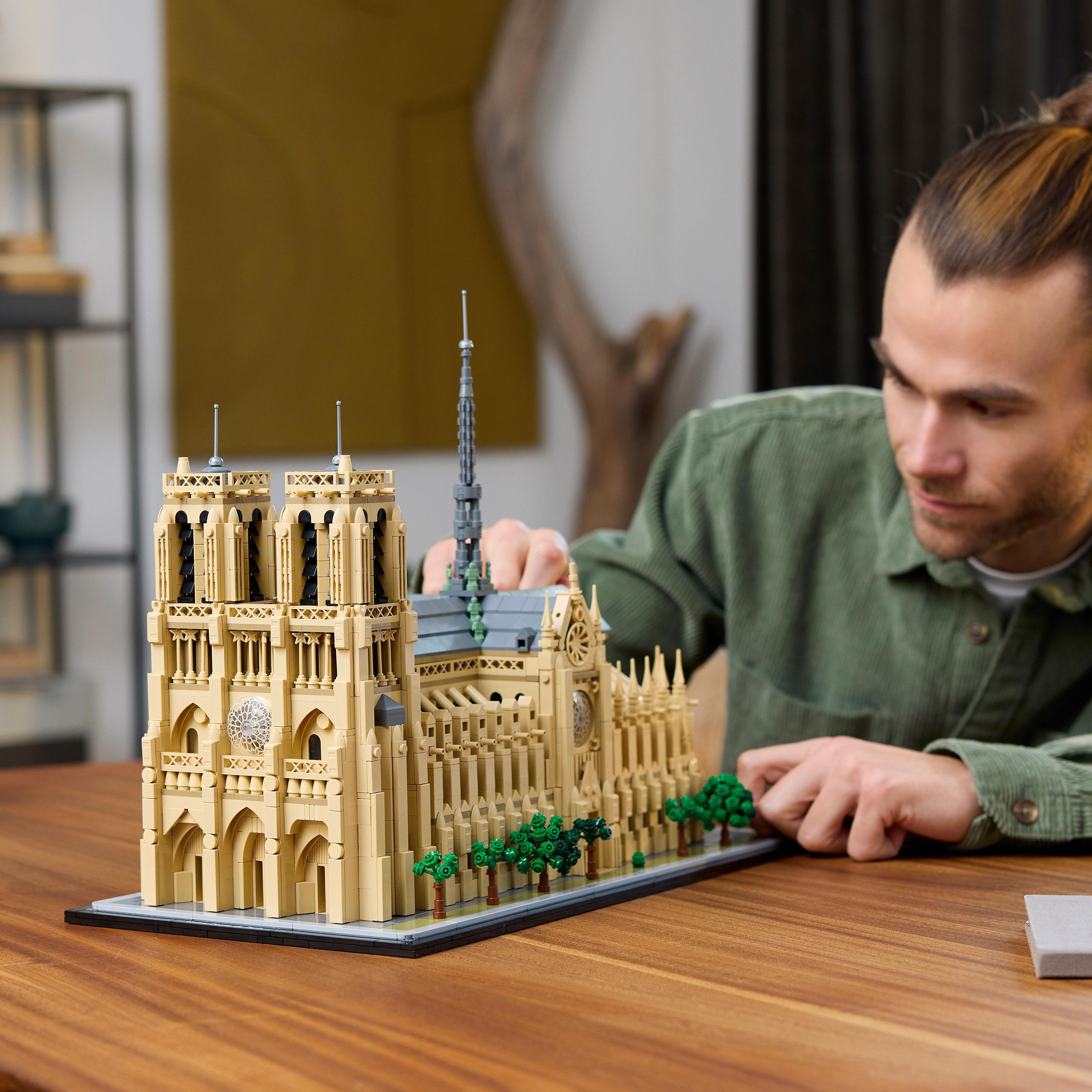 Mann baut Lego-Modell der Notre Dame Kathedrale auf einem Tisch.