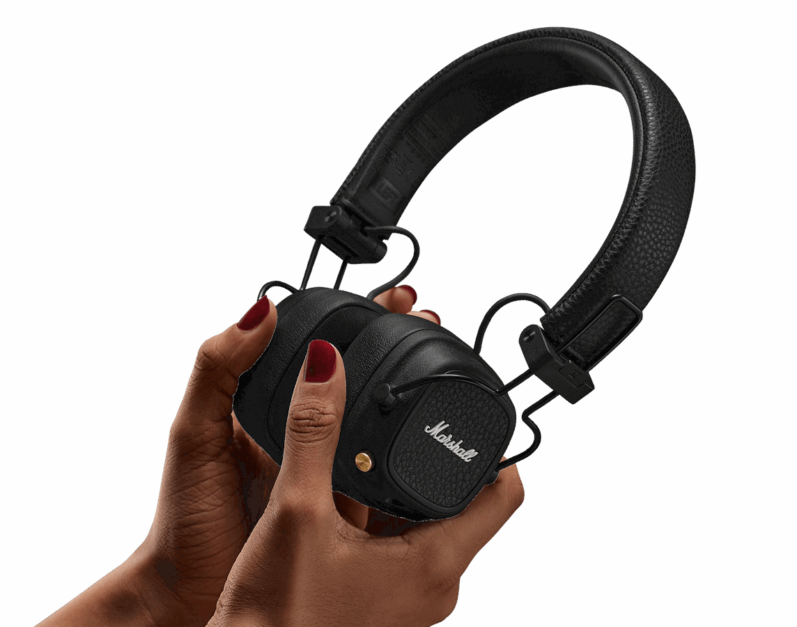 Czarne słuchawki Marshall trzymane w dłoniach. Widoczny czerwony lakier do paznokci. Białe tło.