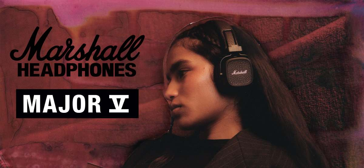 Osoba nosi słuchawki Marshall. Tekst: Marshall HEADPHONES, MAJOR V. Tło w odcieniu różu.