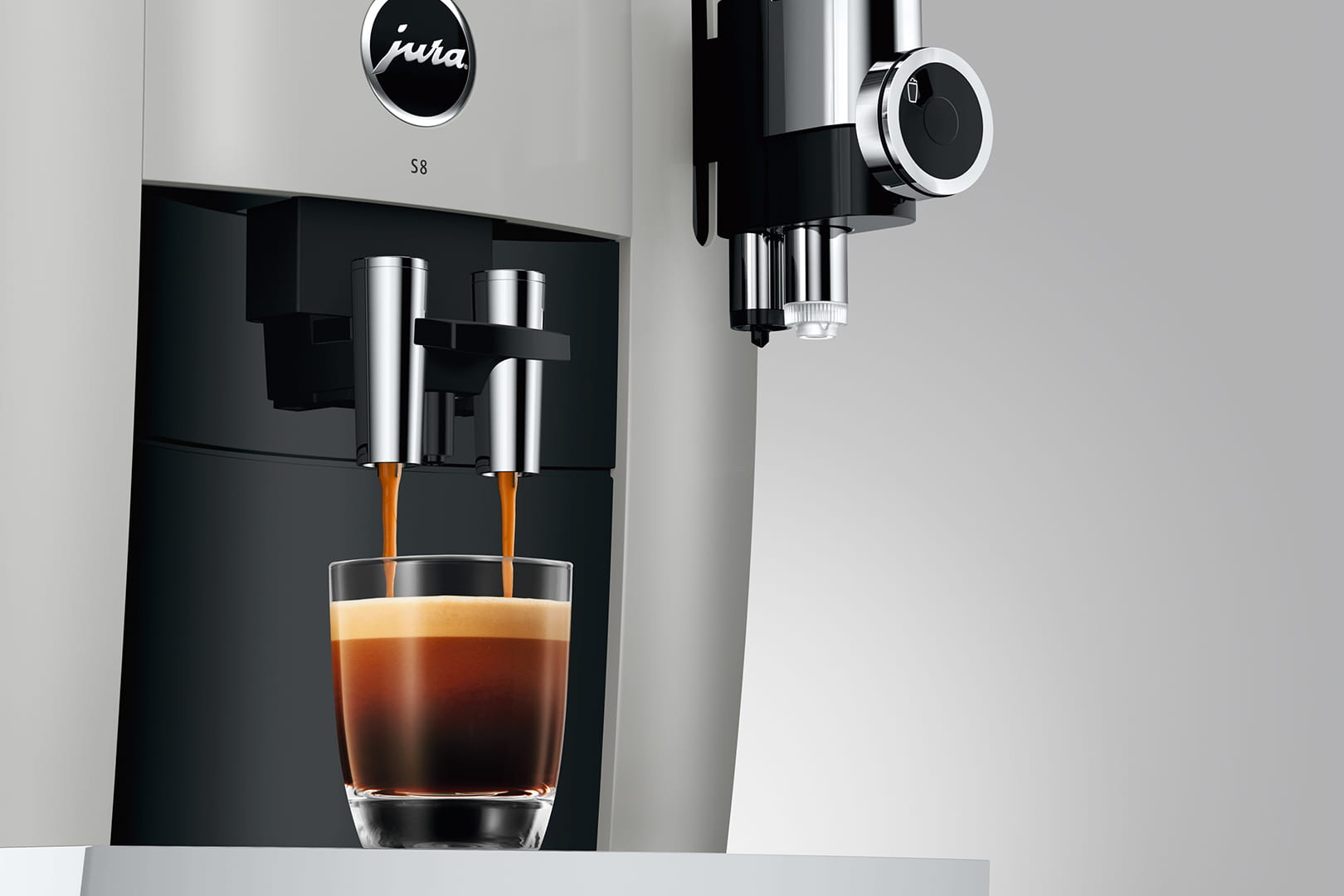 Una macchina per espresso che eroga caffè in un bicchiere. La macchina è bianca, il caffè scuro.