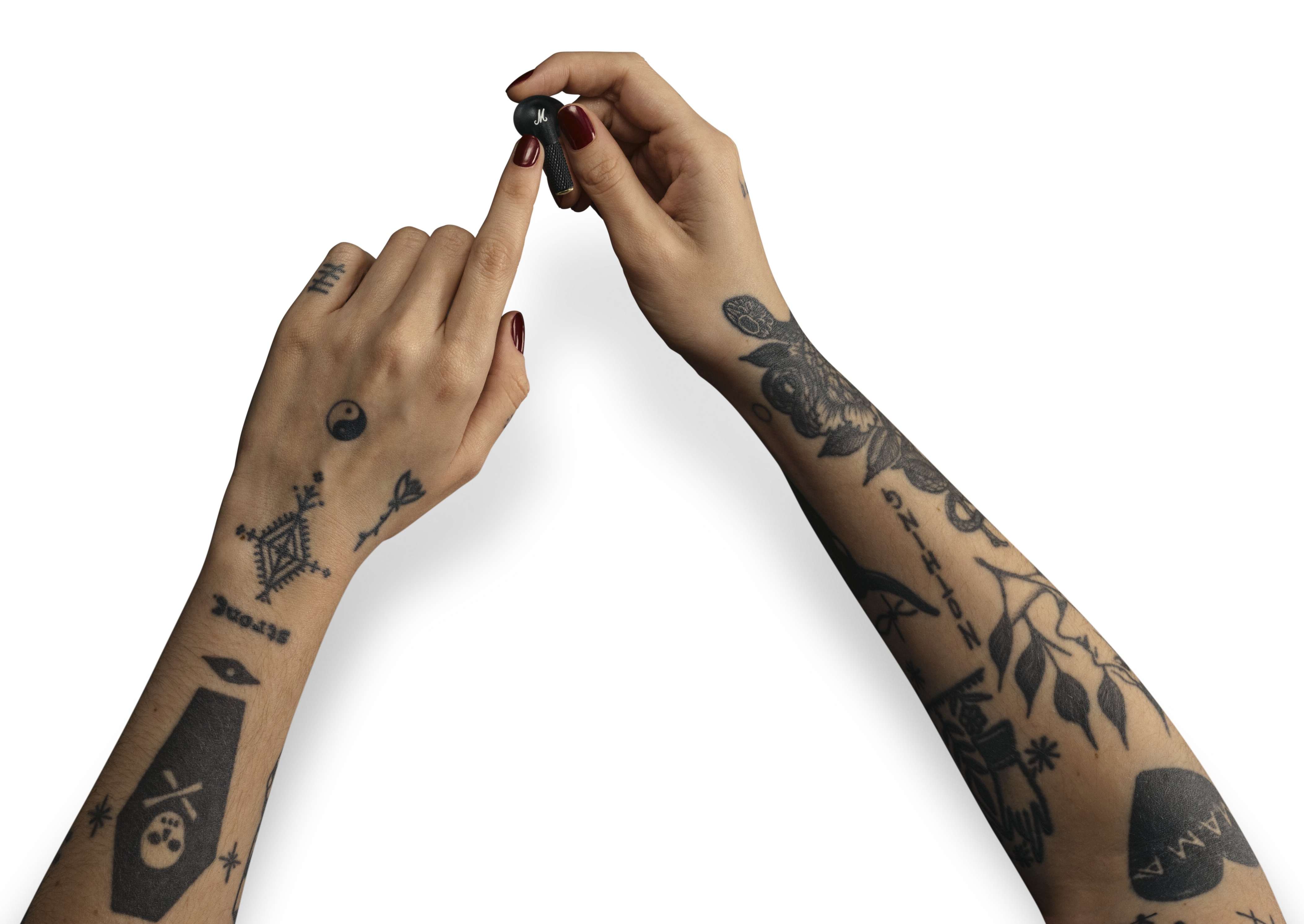 Dwie dłonie z tatuażami trzymają słuchawkę. Dłonie są na białym tle.