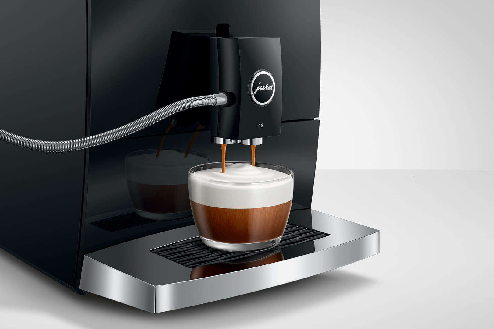 Macchina da caffè Jura C8 nera che eroga caffè in un bicchiere. Sfondo bianco.
