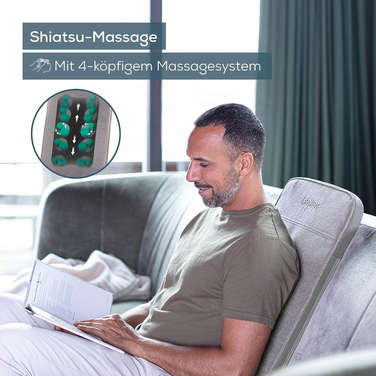 Homme lisant un livre, utilisant un appareil de massage Shiatsu sur un canapé.
