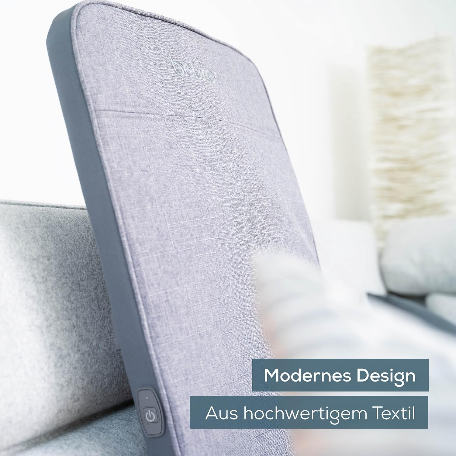 Coussin de massage gris, gros plan, montrant le design et la marque, sur un canapé.