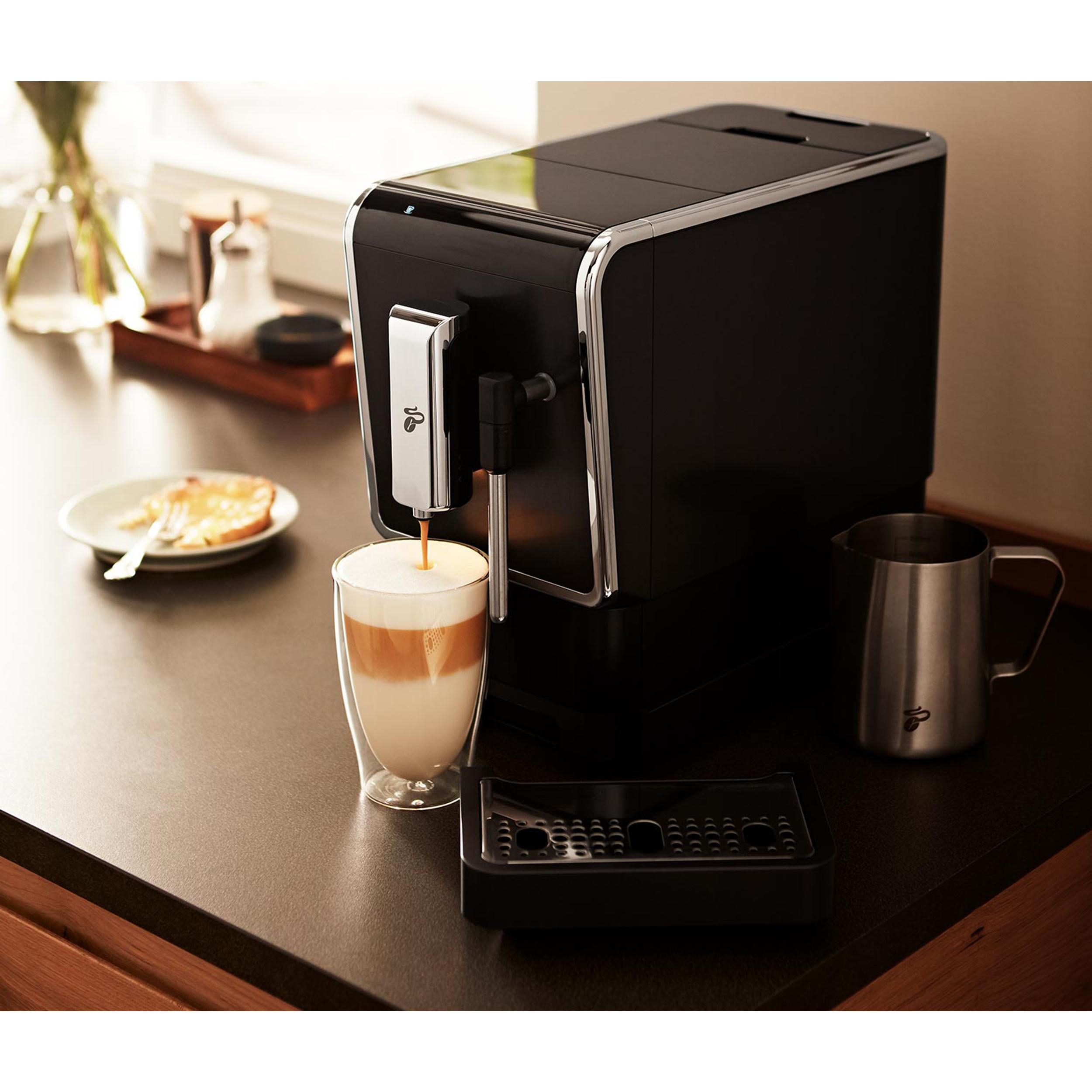 Kaffeemaschine gießt Latte in ein Glas, mit Zubehör.