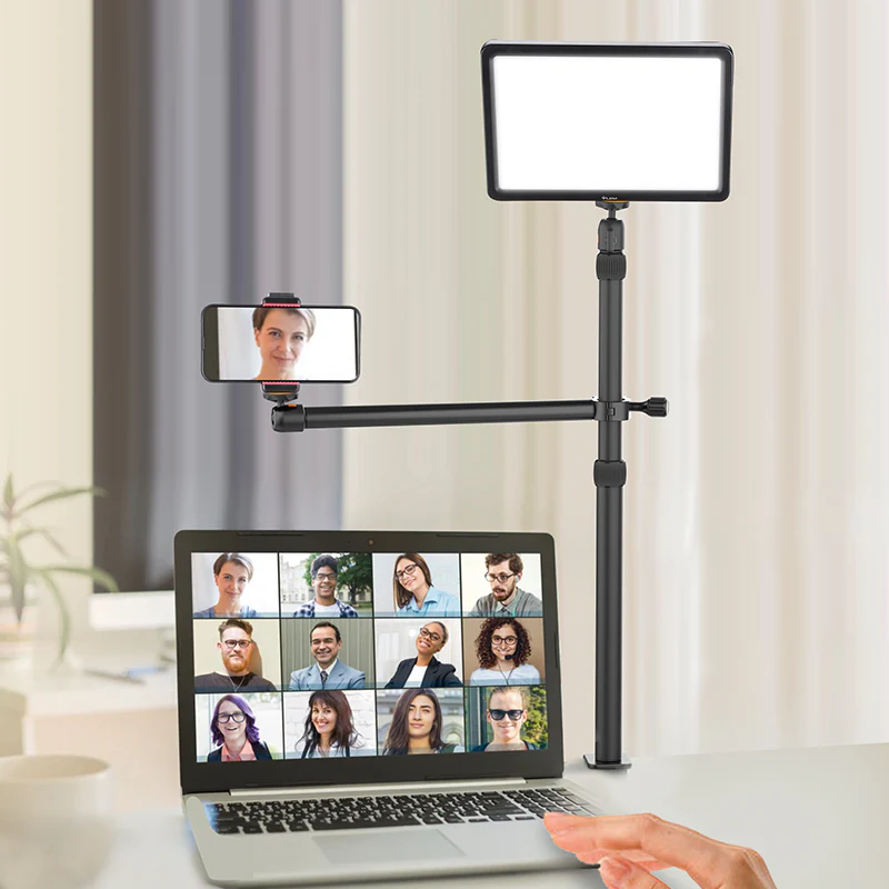 Egy laptop videohívást jelenít meg. Egy telefon és egy lámpa is látható.