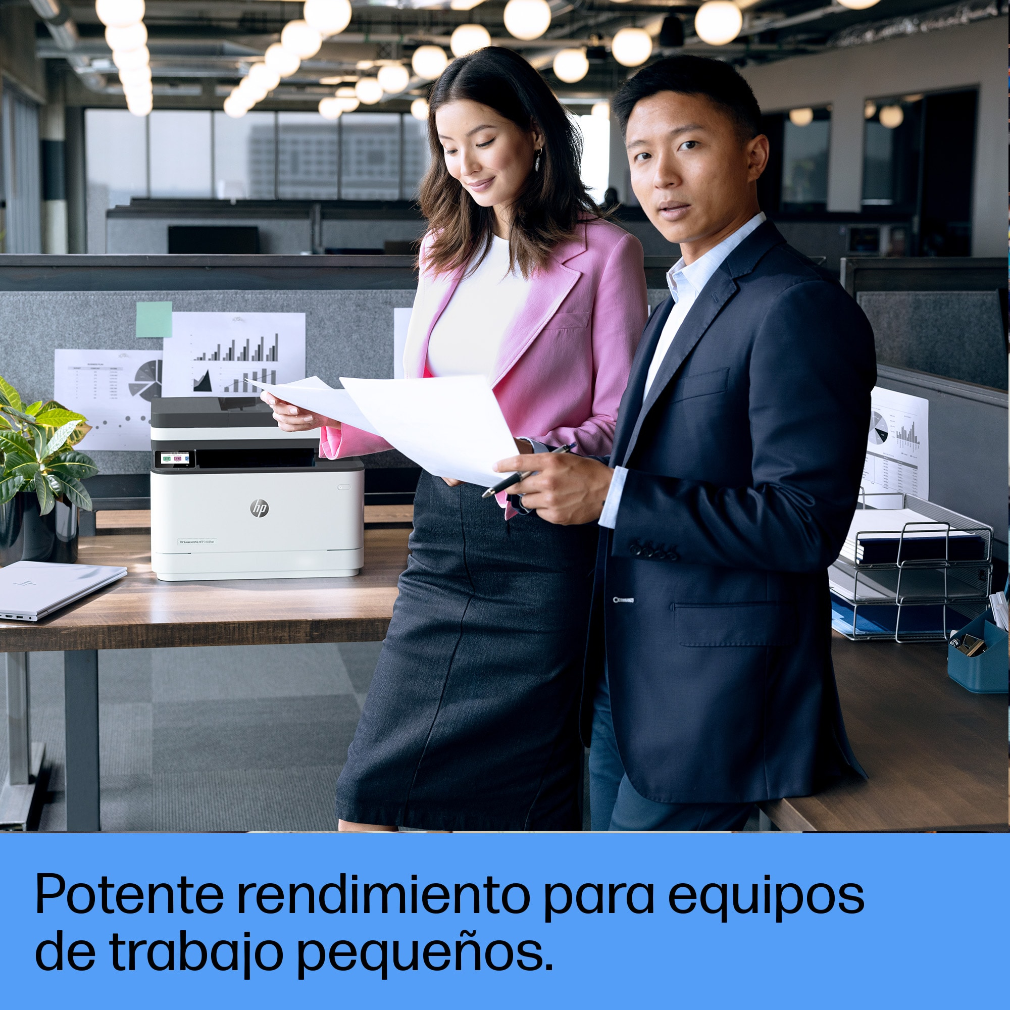 Dos personas en un entorno de oficina, mirando documentos. Una impresora está en un escritorio.