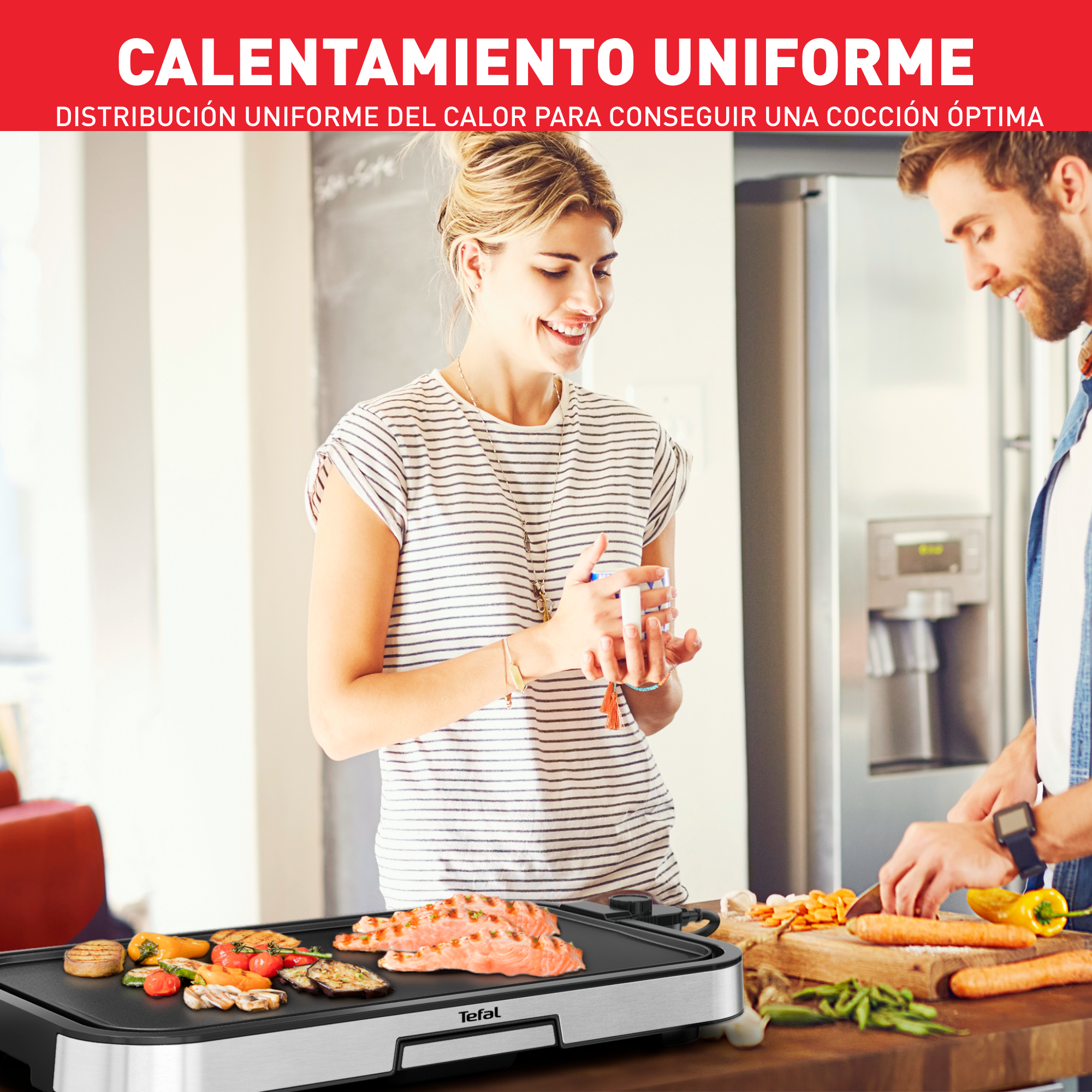 Pareja cocinando en una parrilla. Mujer sosteniendo una taza, hombre cortando verduras.