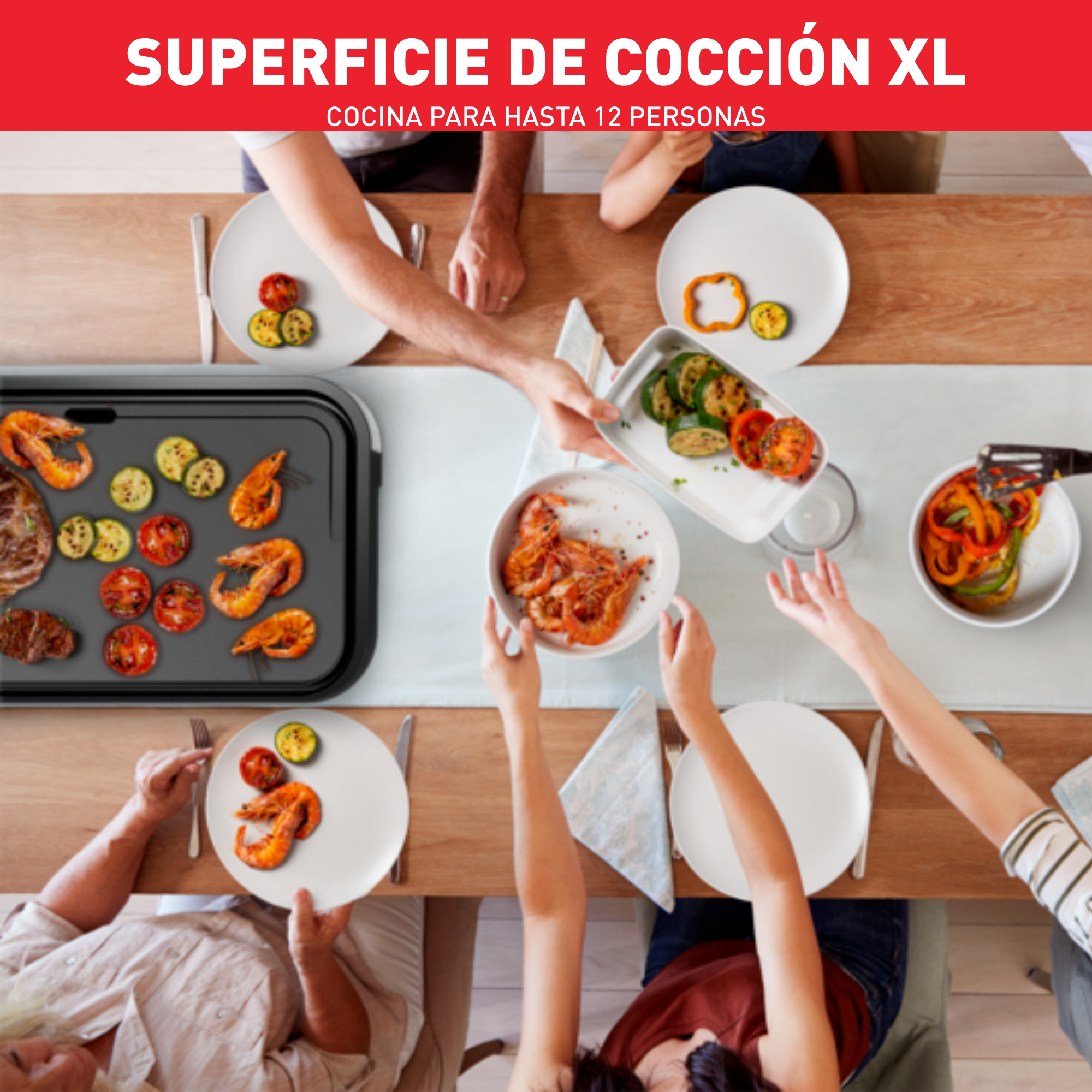 Vista cenital de mesa con comida, gente alcanzando platos, superficie de cocción en medio.