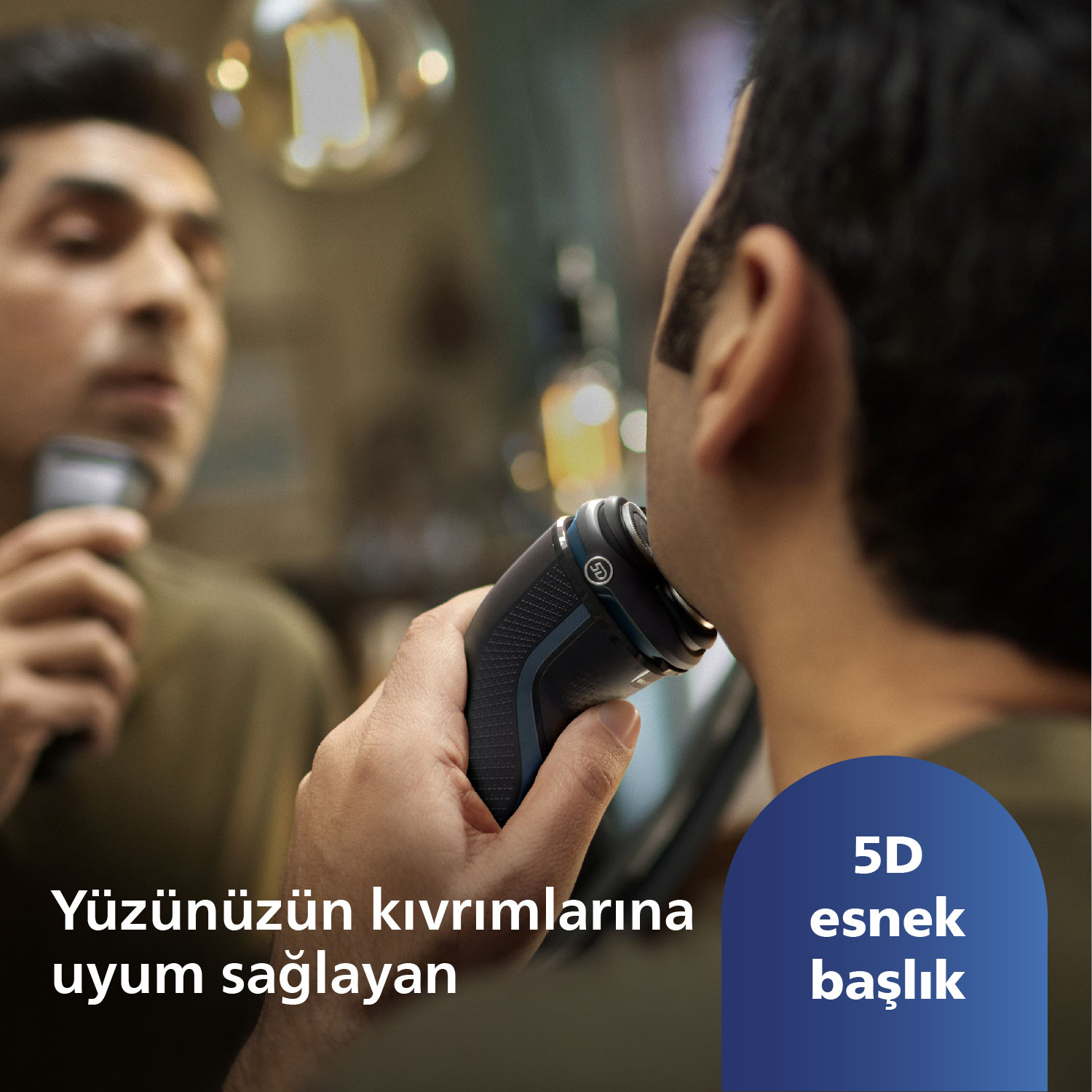 Bir adam, elektrikli bir tıraş makinesiyle yüzünü tıraş ediyor, yakın çekim. Metin 'Yüz hatlarına uyum sağlar' diyor.