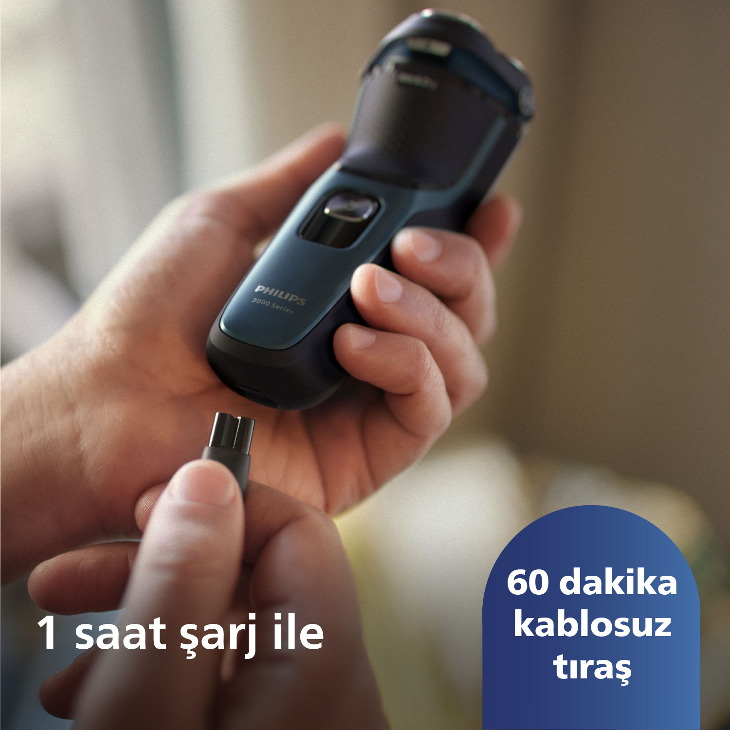 Bir kişi mavi ve siyah bir elektrikli tıraş makinesi tutuyor, şarj portu görünür durumda.