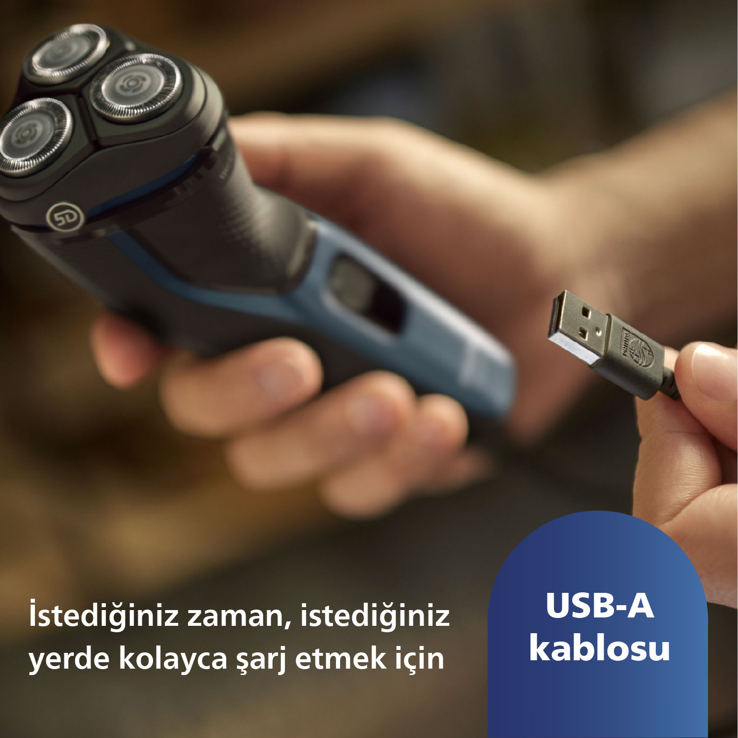 Bir adam tıraş makinesi ve USB-A kablosu tutuyor.