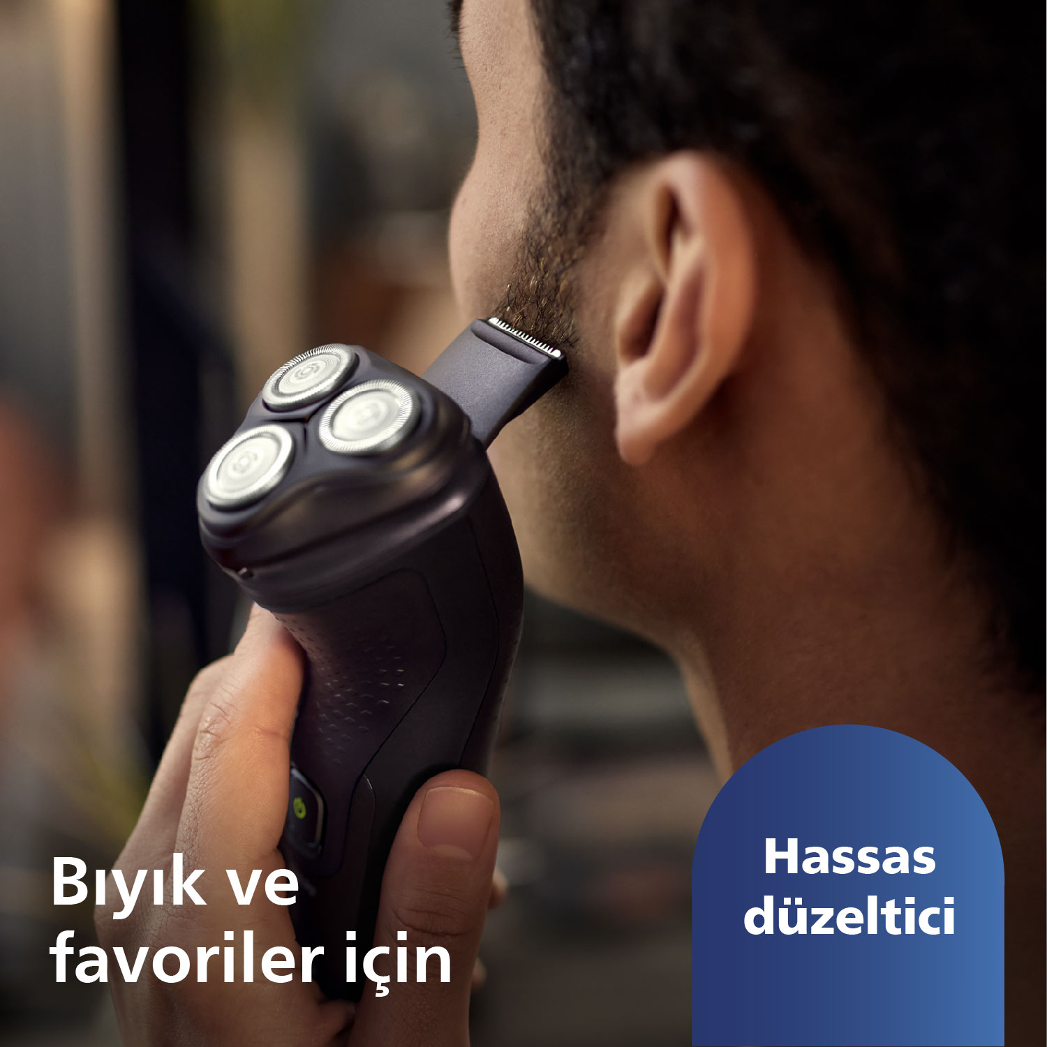 Bir adam, siyah bir Philips elektrikli tıraş makinesiyle favorilerini tıraş ediyor. Türkçe metin dahil.