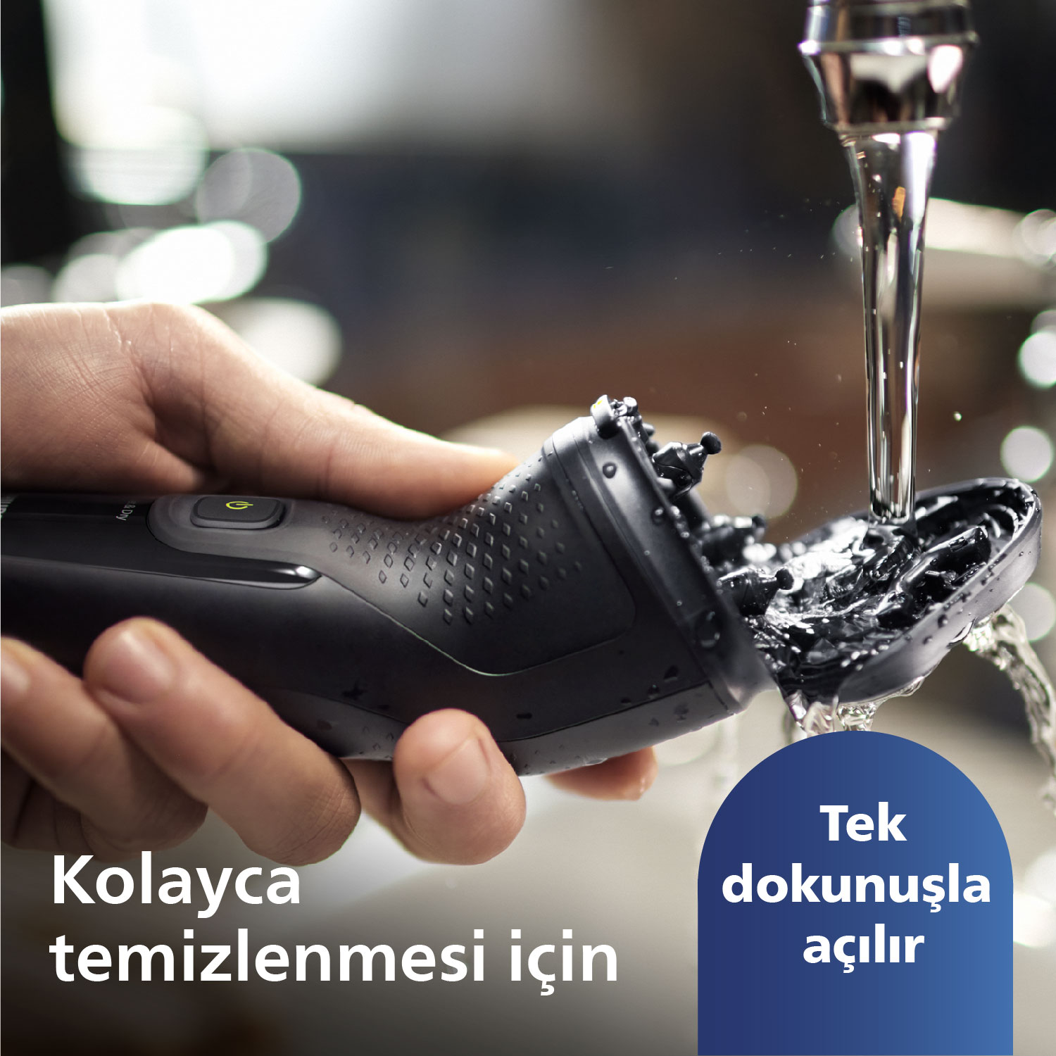 Siyah tıraş makinesi akan su altında temizleniyor. Su akışı gösteriliyor.