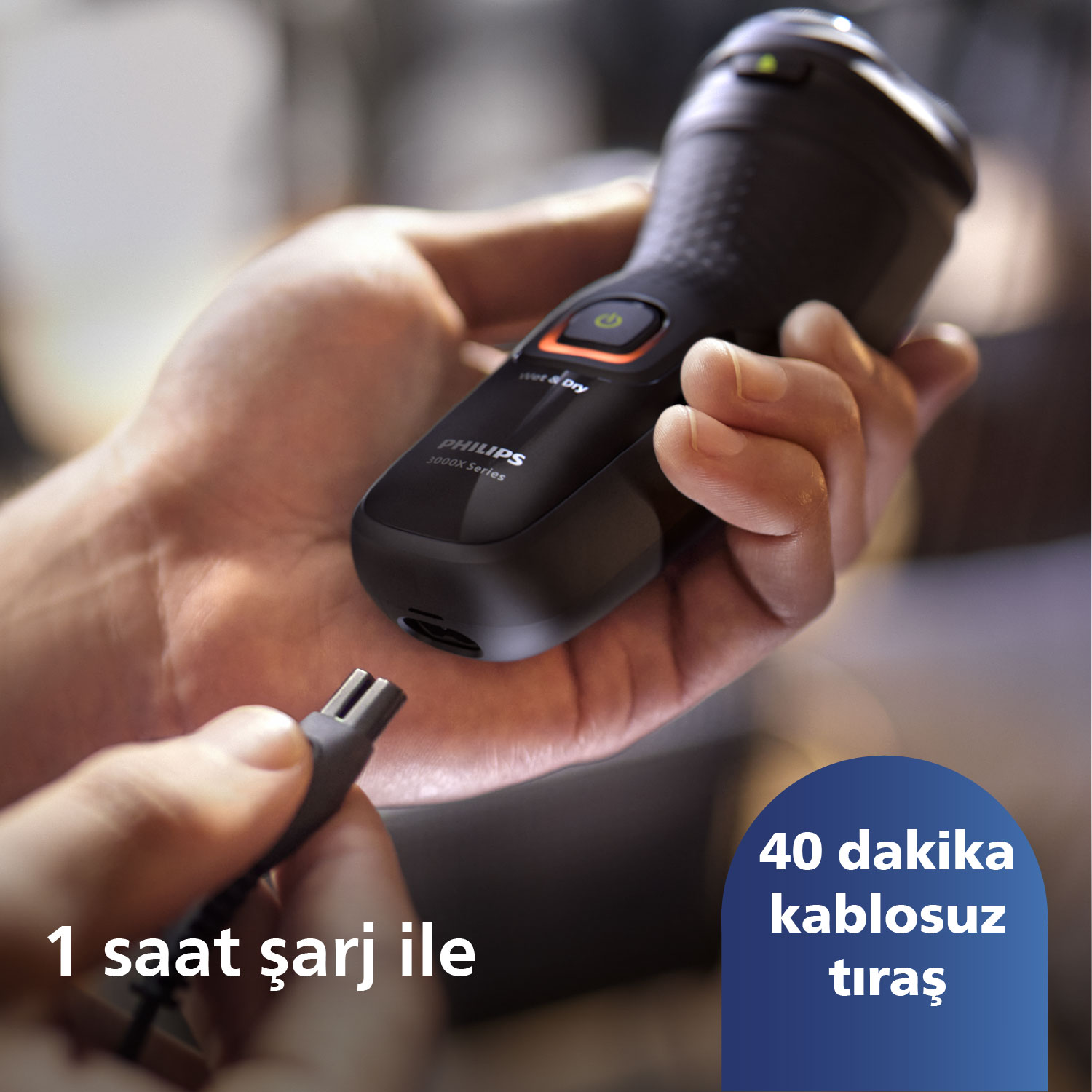 Bir eldeki siyah bir Philips tıraş makinesi, bir şarj kablosu ve mavi bir metin kutusu.