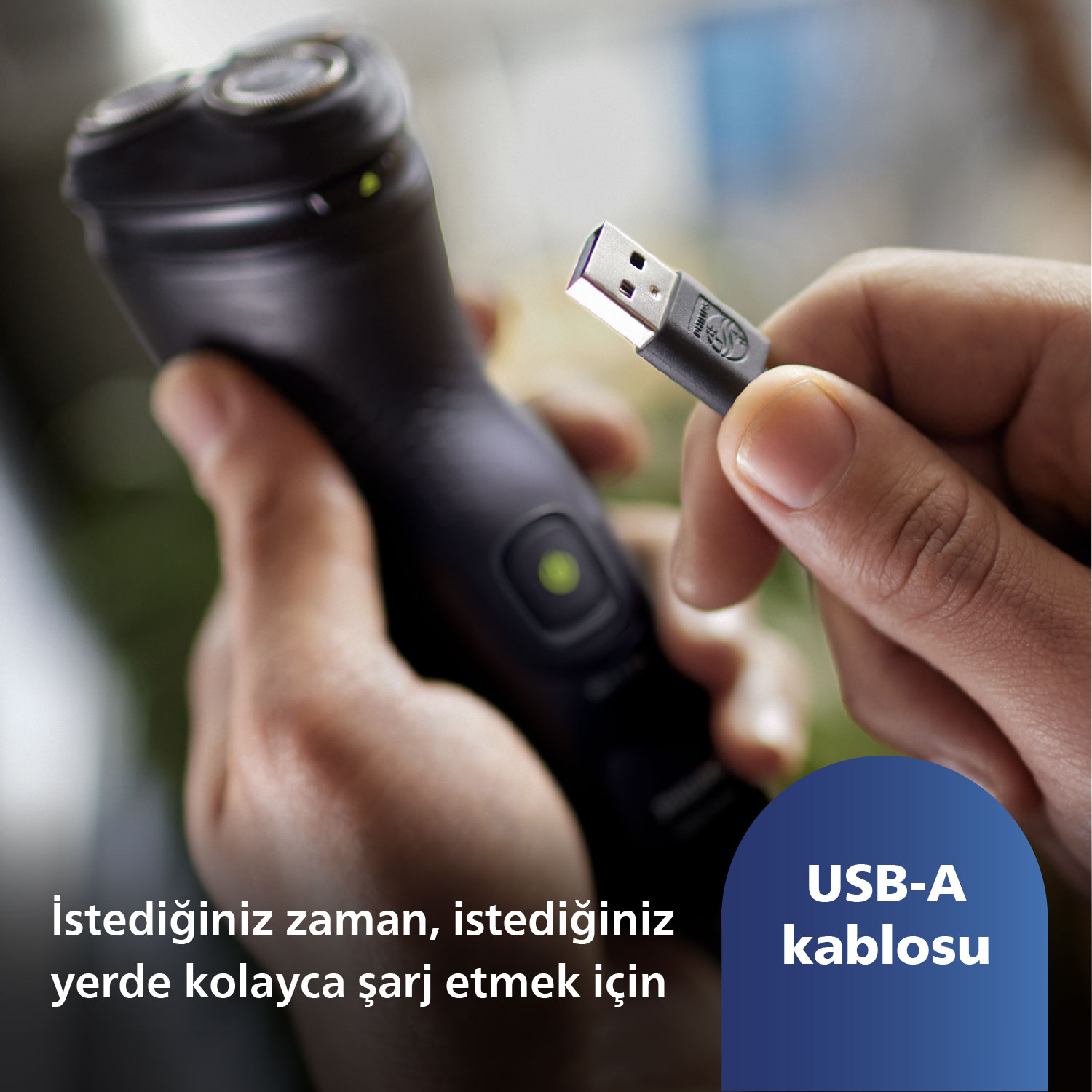 Bir kişi, USB-A kablosu olan siyah bir tıraş makinesi tutuyor. Kablo tıraş makinesine takılı.