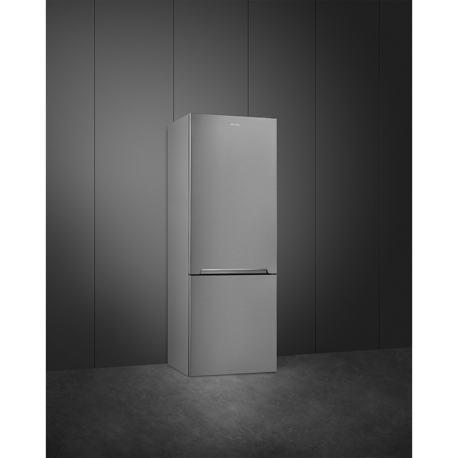 Un frigorifero Smeg in acciaio inossidabile in piedi su un pavimento grigio contro un muro grigio.