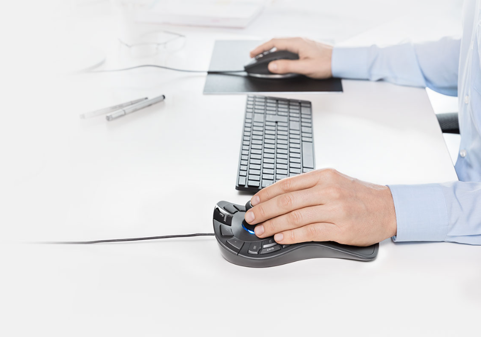 Le mani di una persona su una scrivania che usano una tastiera e un mouse ergonomico unico.