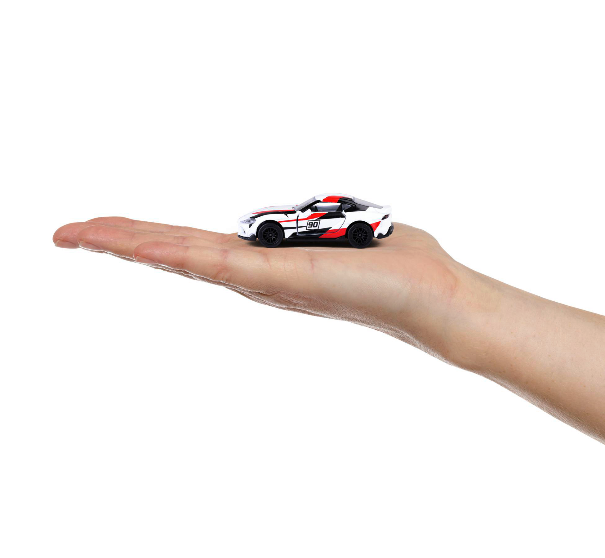 Ein kleines Spielzeugauto, weiß mit roten und schwarzen Akzenten, liegt auf einer offenen Hand vor weißem Hintergrund.