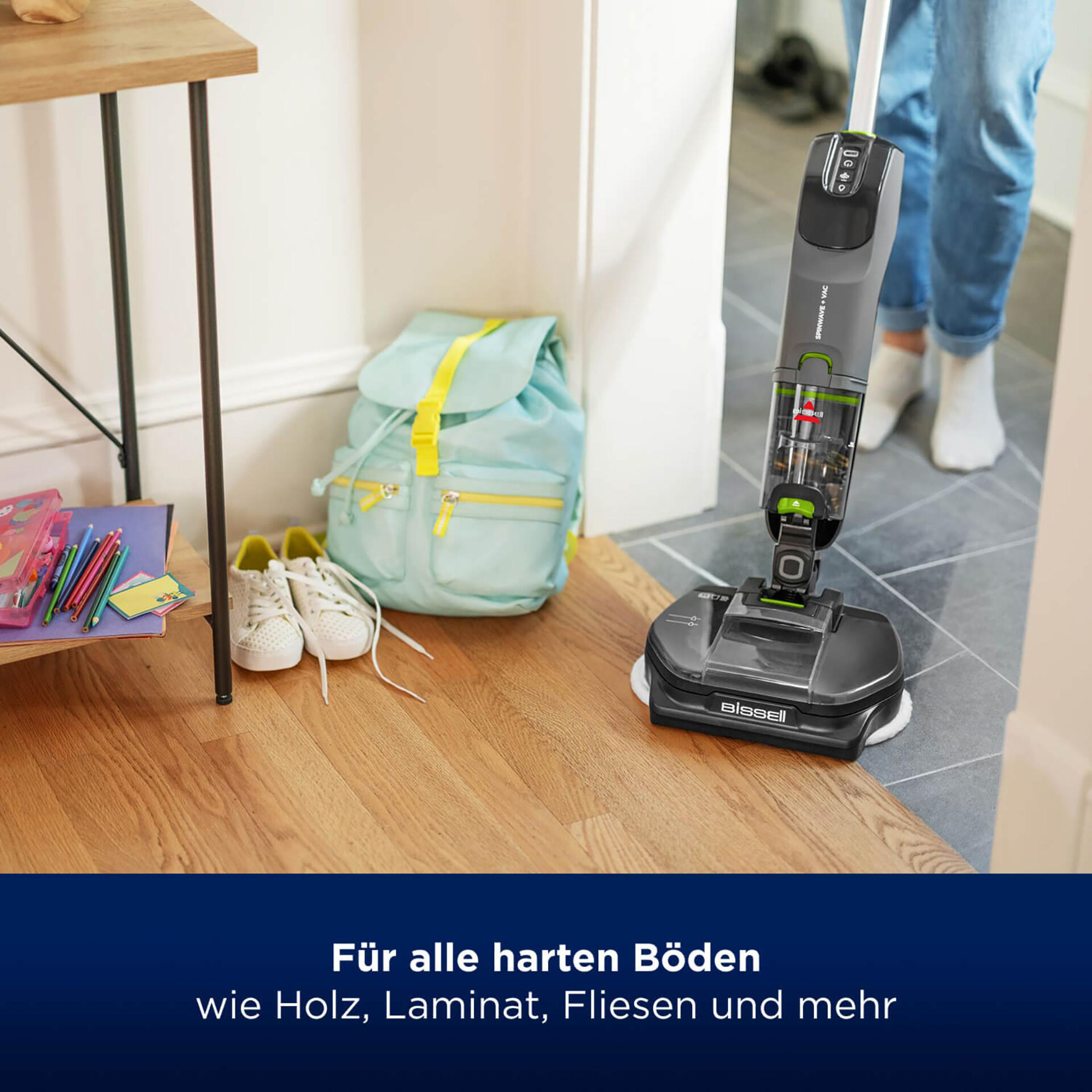 Person reinigt Holzboden mit Gerät; andere Gegenstände sichtbar.