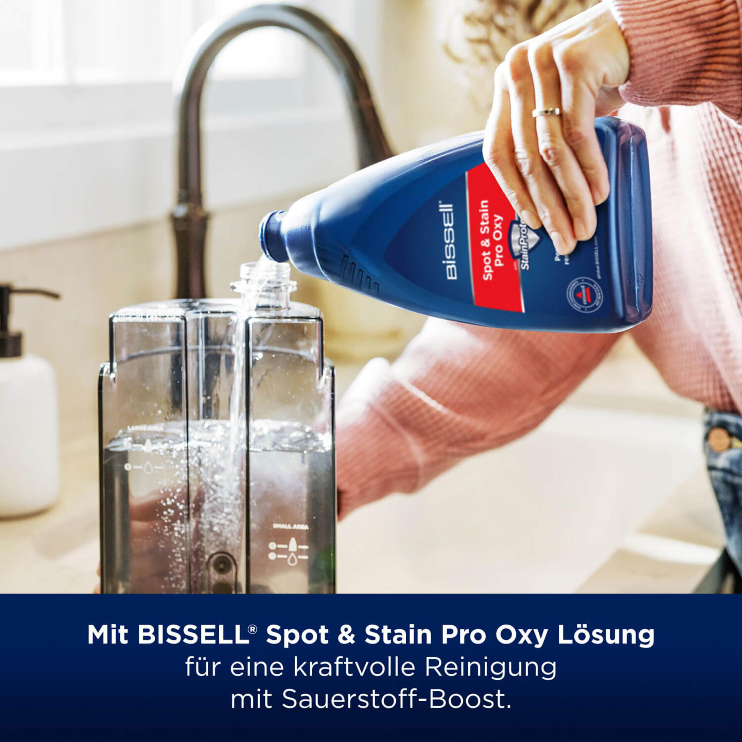 Eine blaue Flasche gießt Reinigungsmittel in einen transparenten Behälter. Im Hintergrund ist ein Waschbecken.