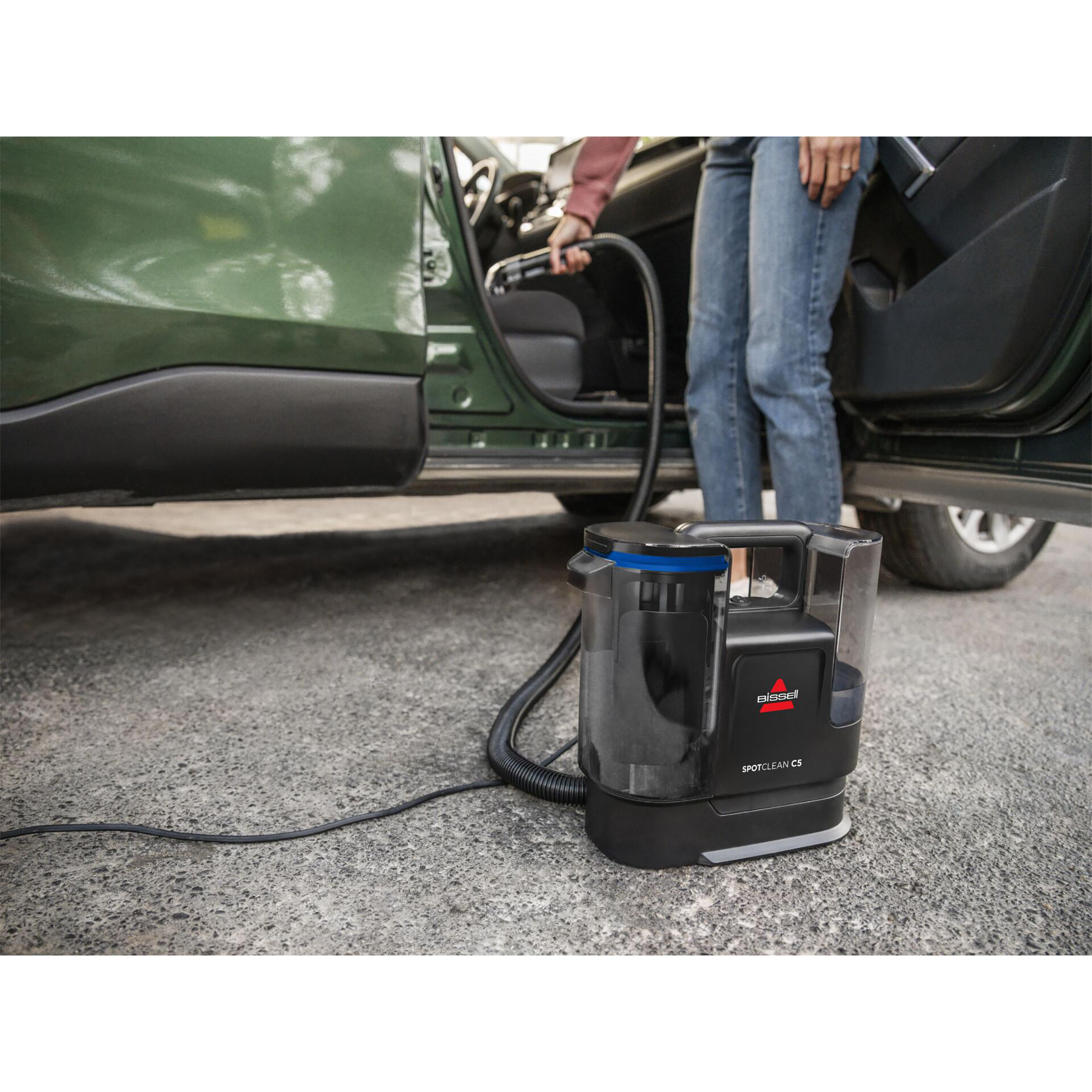 Eine Person saugt das Innere eines Autos mit einer Bissell SpotClean C5 Maschine.