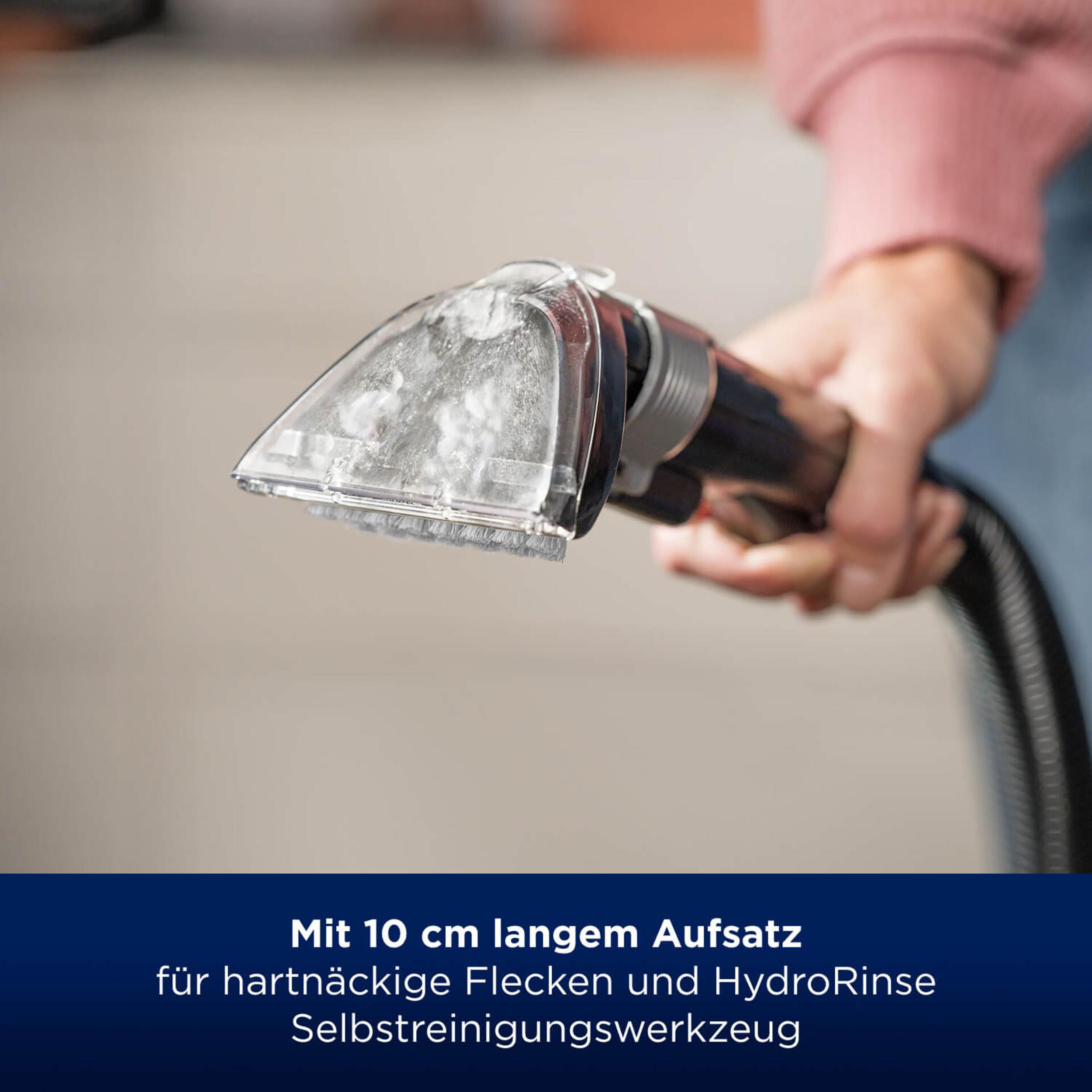 Eine Hand hält einen Staubsaugerkopf. Text: Mit 10 cm langem Aufsatz.