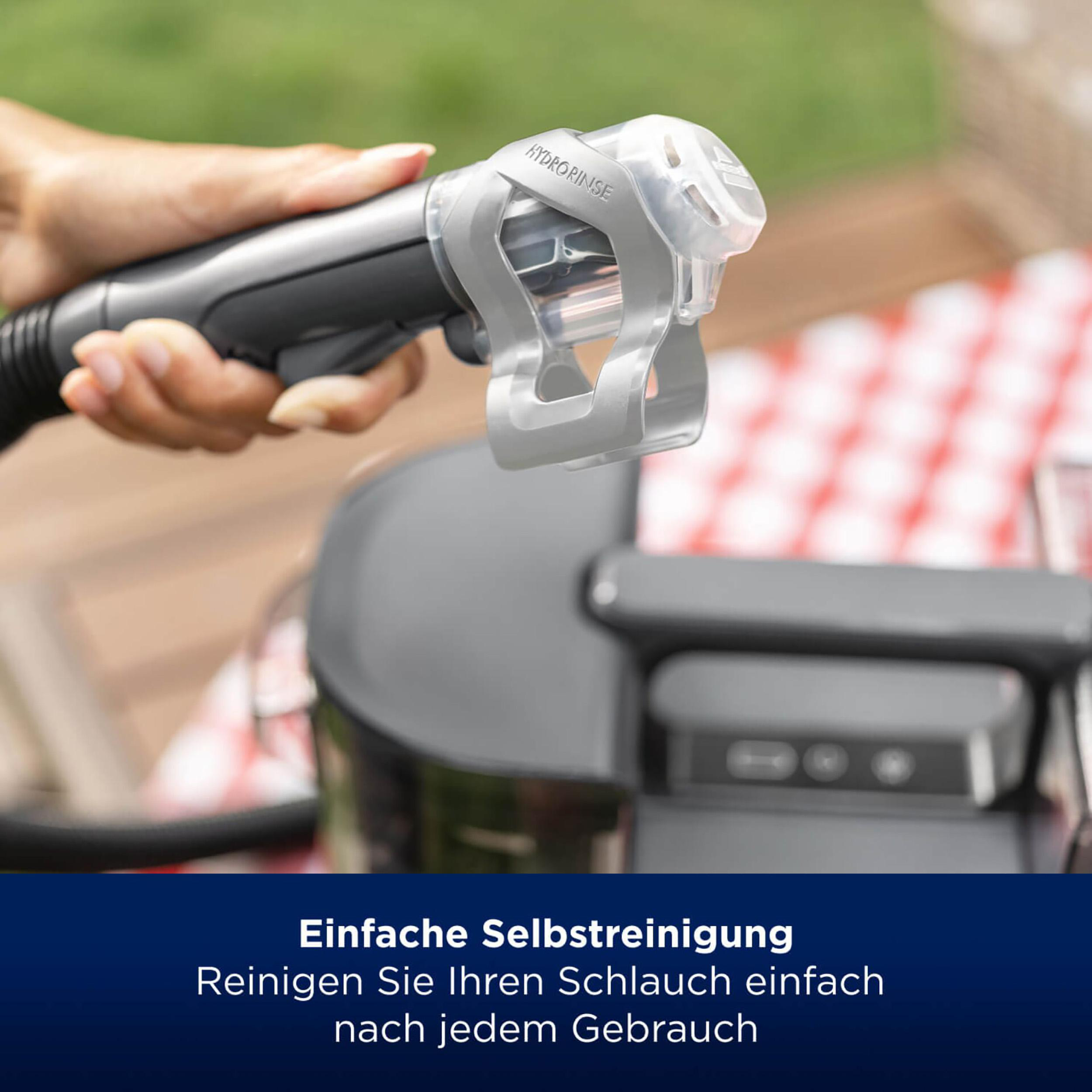 Person hält ein HydroRinse-Gerät neben einem Grill.