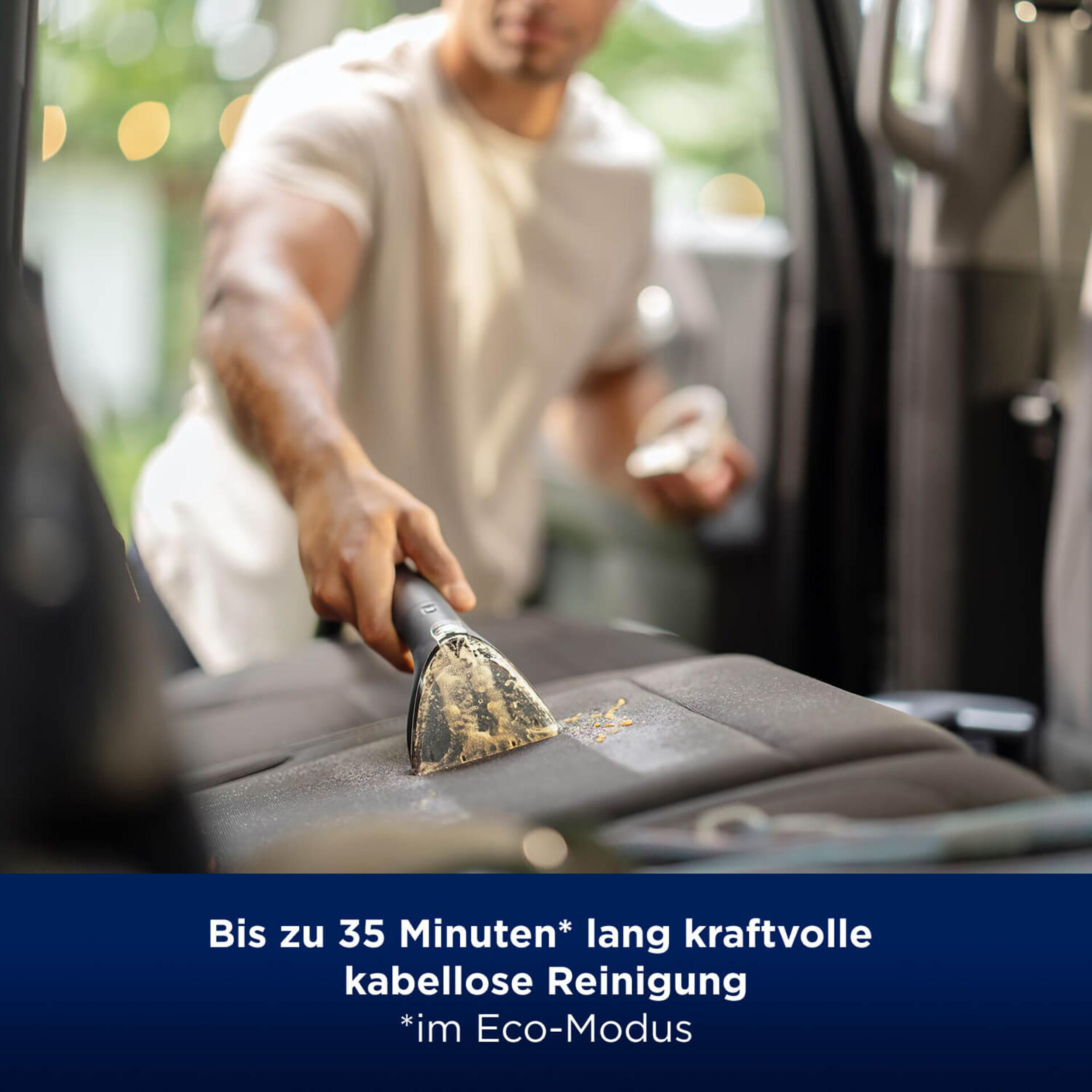 Ein Mann reinigt einen Autositz mit einem Staubsauger. Text auf Deutsch unten.