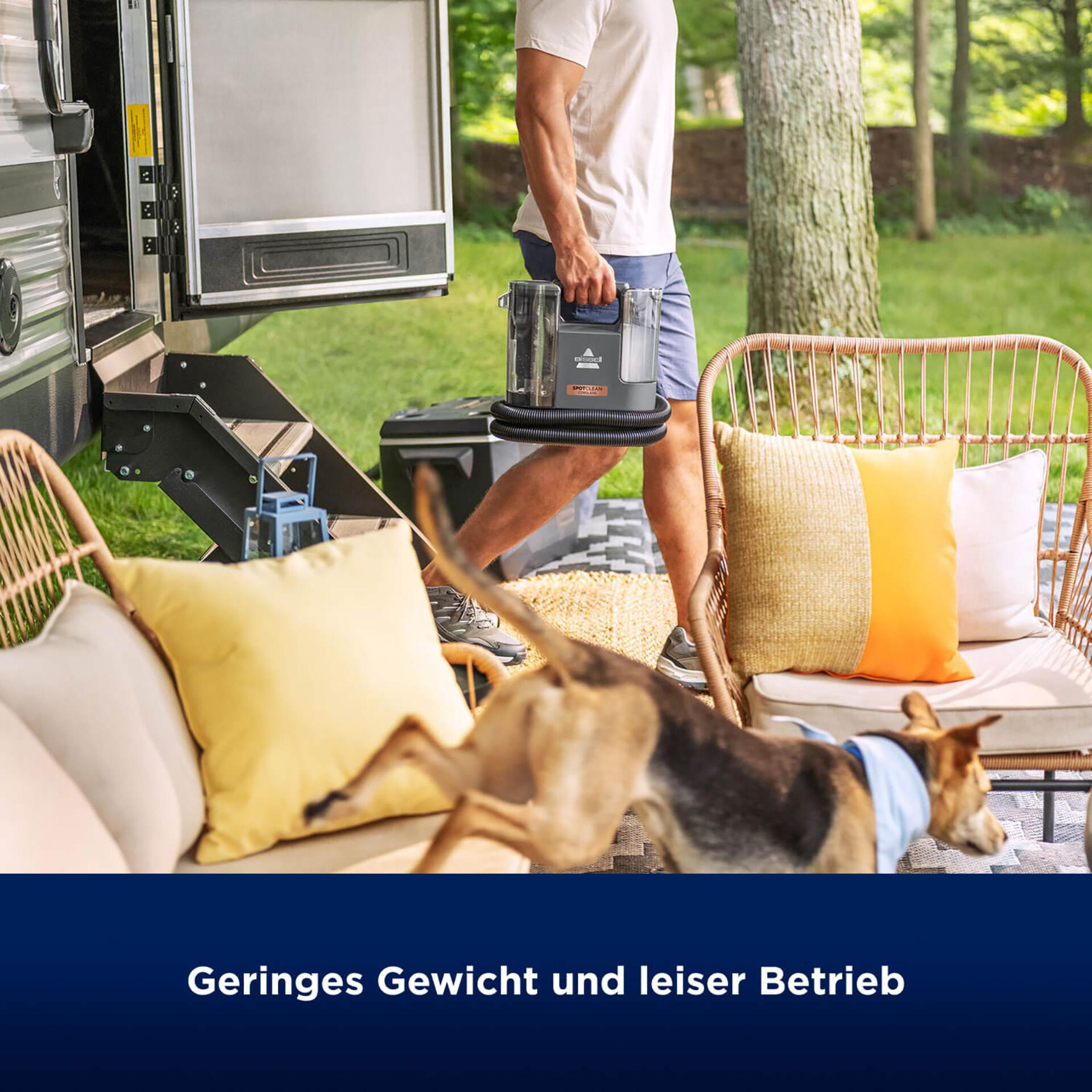 Mann mit Staubsauger im Freien. Hund rennt.