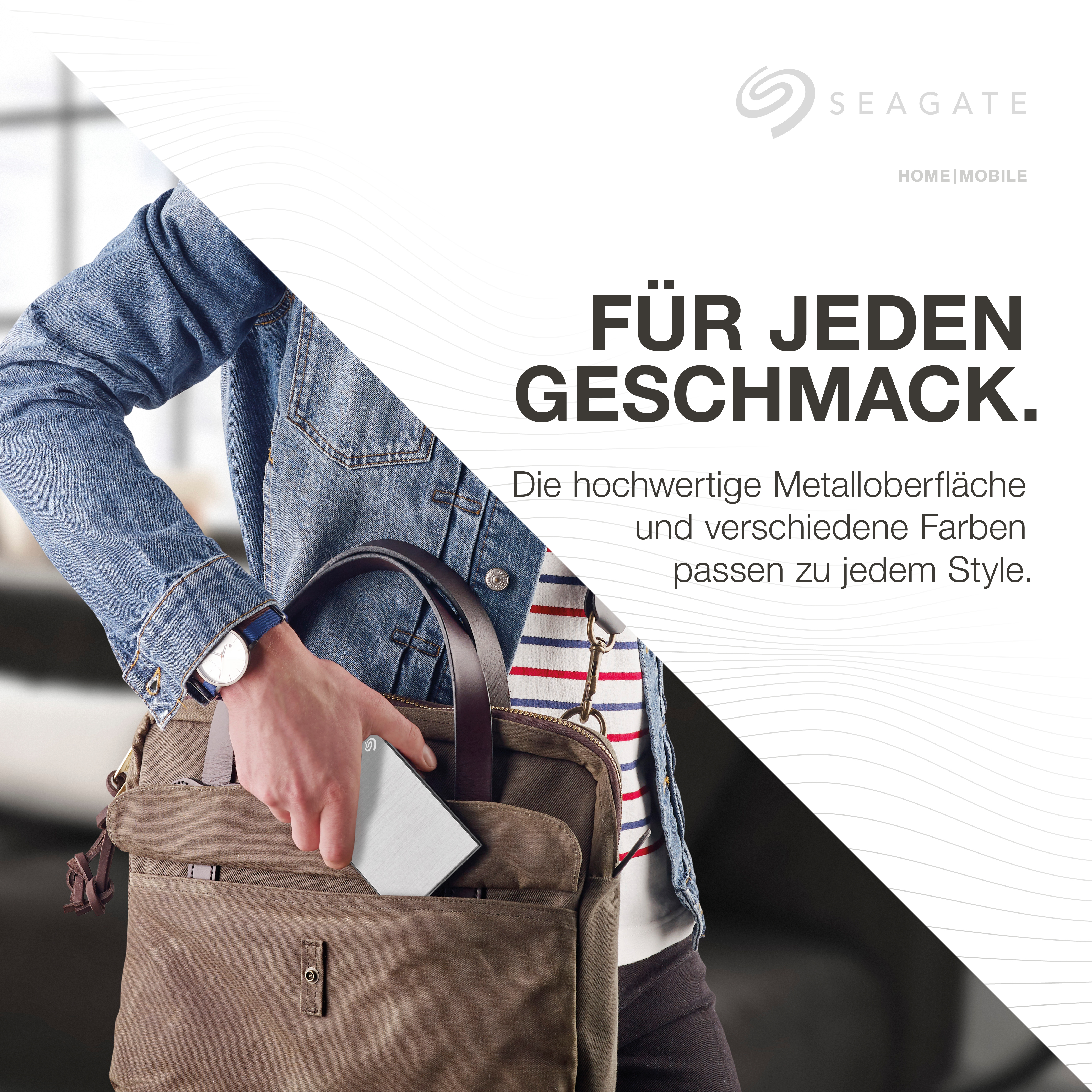 Hand hält silberne externe Festplatte und Ledertasche.