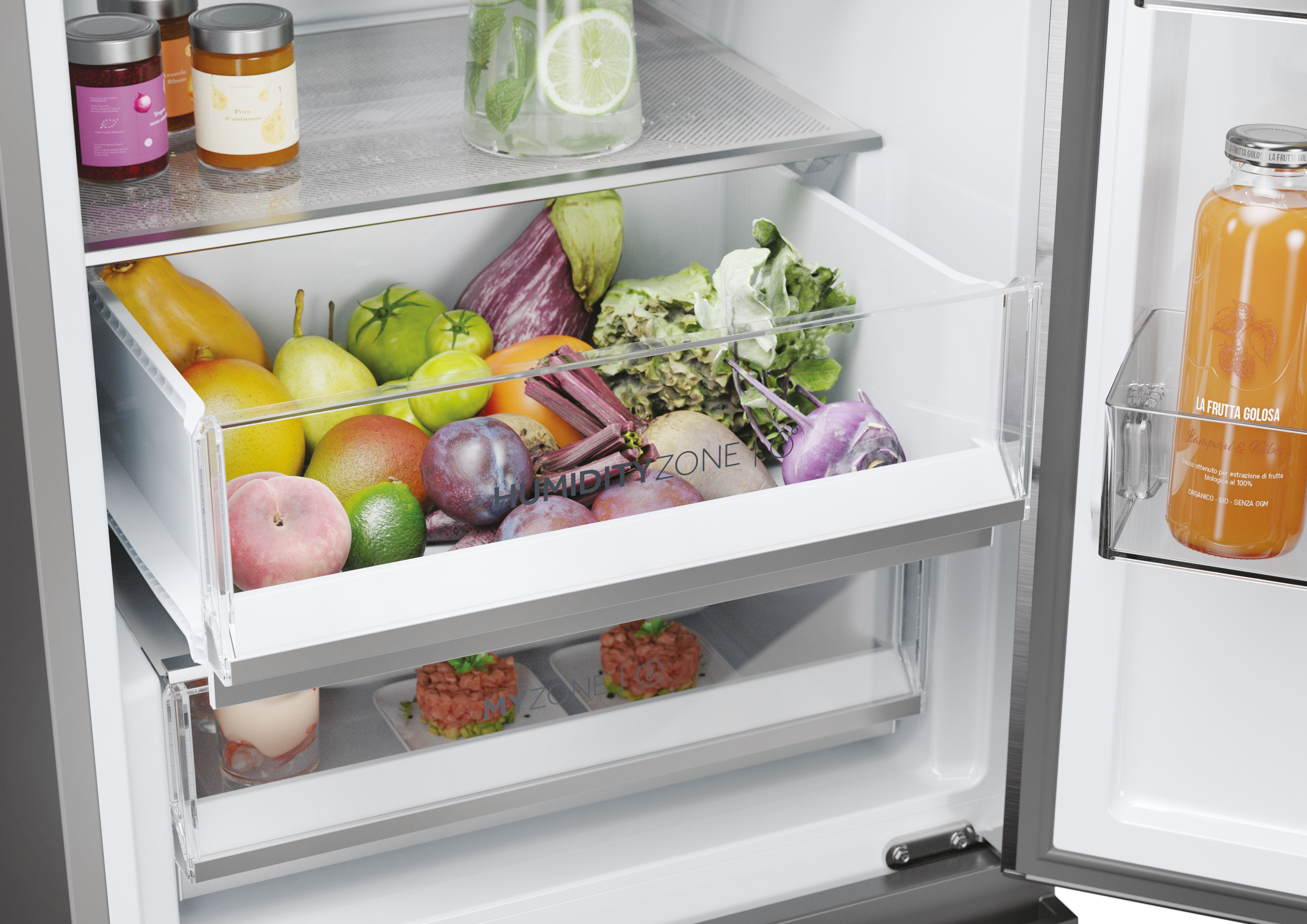 Refrigerador abierto, lleno de frutas y verduras en cajones, frascos en el estante superior, jugo de naranja.