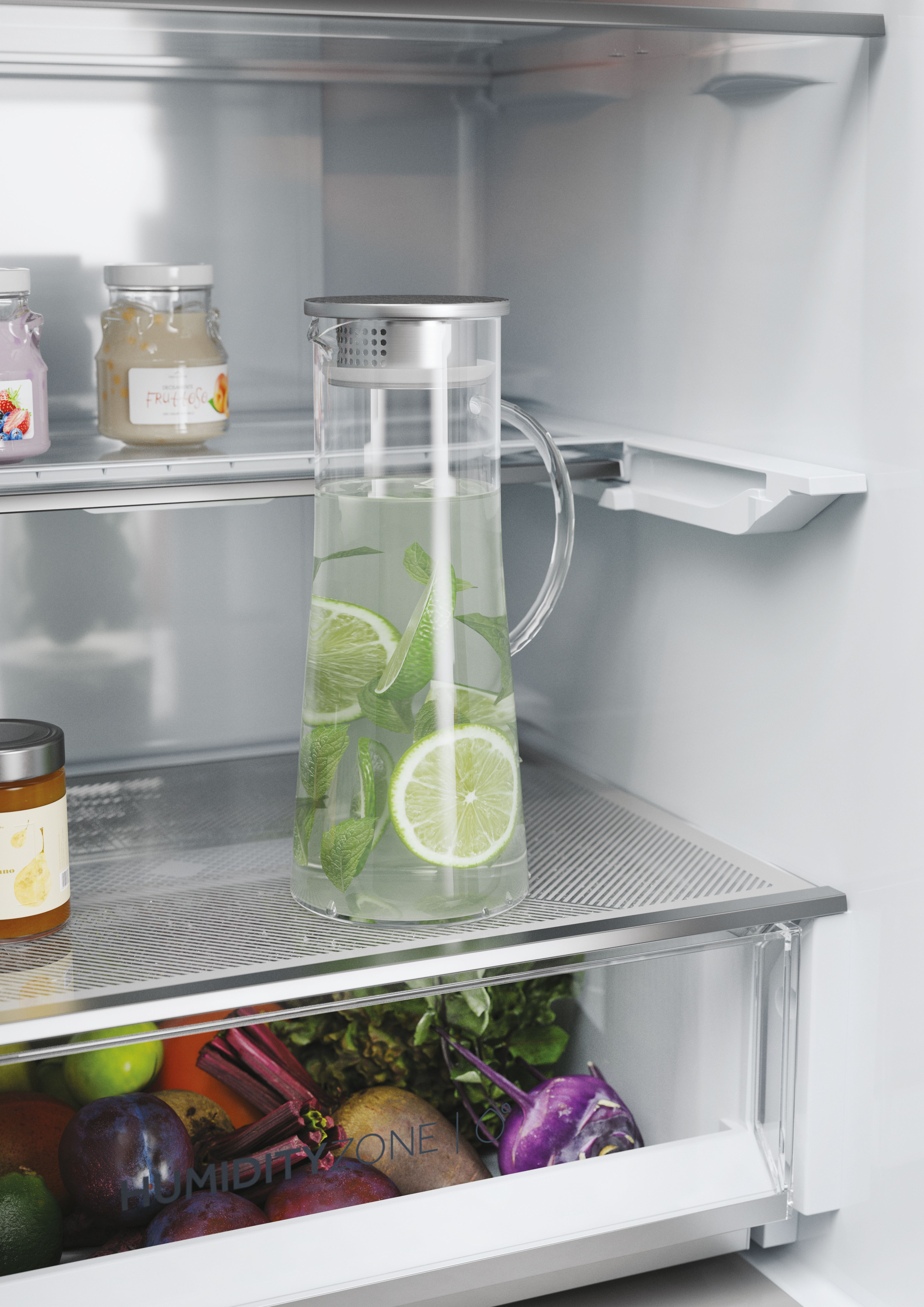 Interior de la nevera con una jarra de agua con limas y un tarro de conservas de fruta.