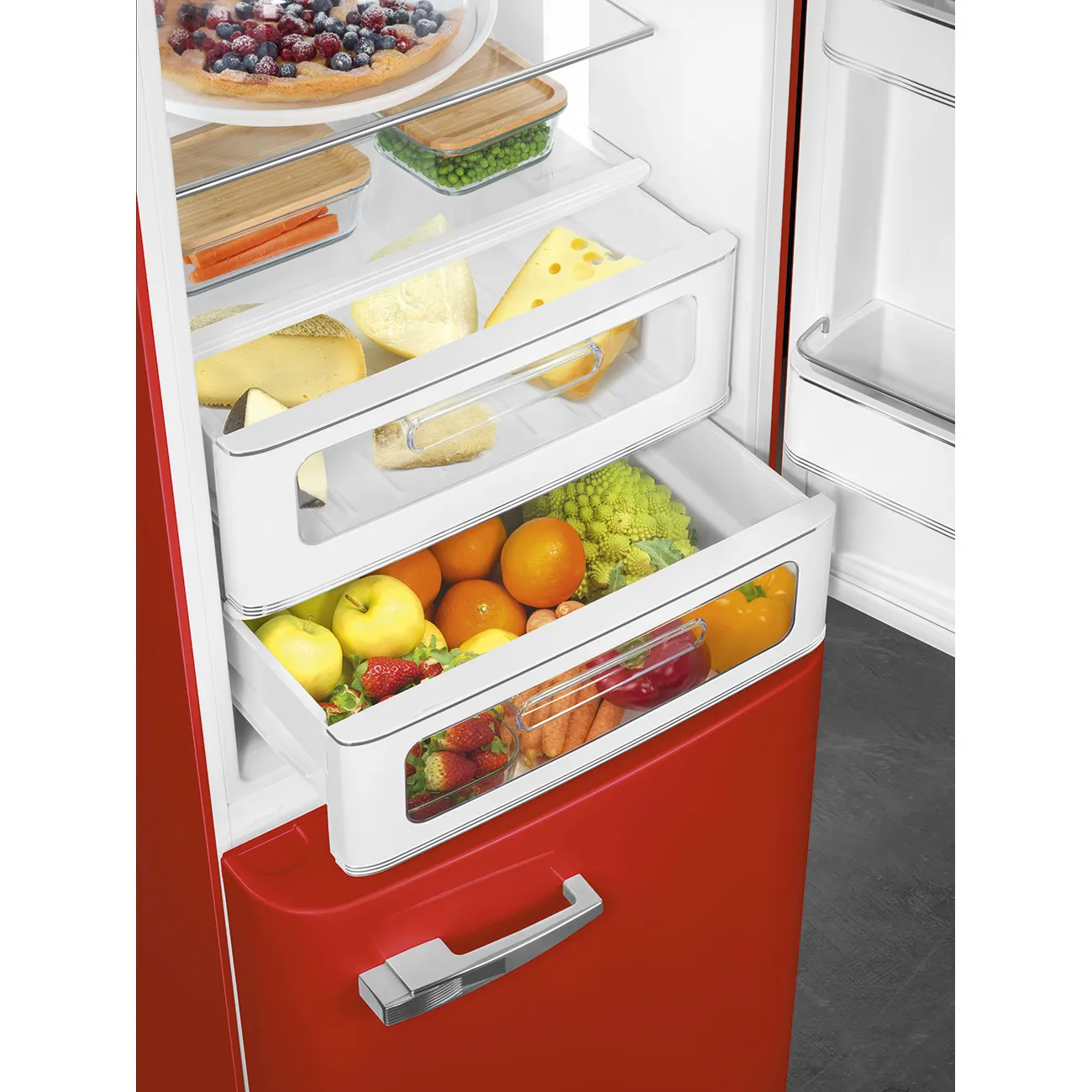 Un refrigerador rojo con cajones abiertos llenos de comida. Se ven frutas, queso y verduras.